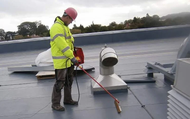 Technician in hi-vis inspecting a commercial roof for leaks