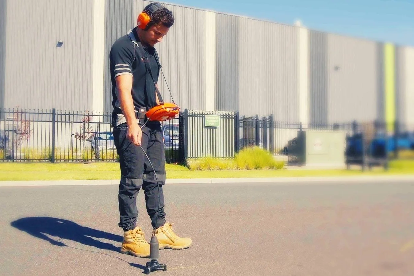 Forensic technician using high-frequency Acoustic Soil Probes for non-invasive slab leak detection under a concrete house foundation to locate hidden pipe bursts.