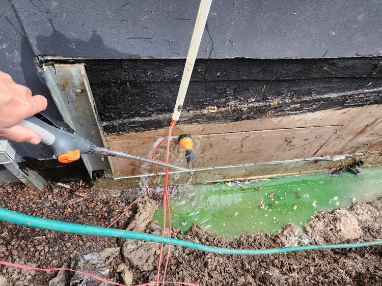Technician probing an exposed water pipe in a trench