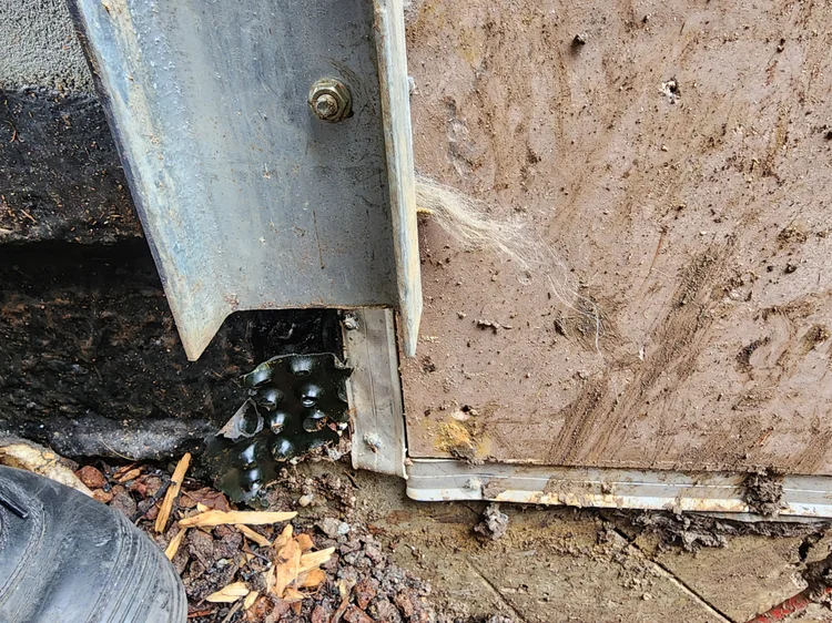 Excavation beside a wall exposing a leaking water pipe