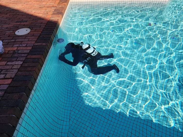 Diver checking a pool shell for leaks underwater
