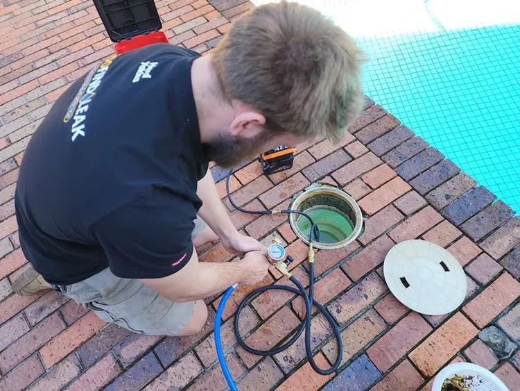 Technician testing a pool skimmer box for a leak