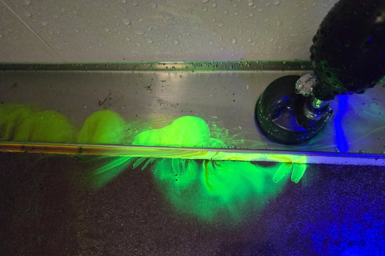 UV tracer dye glowing on a roof edge during a leak test