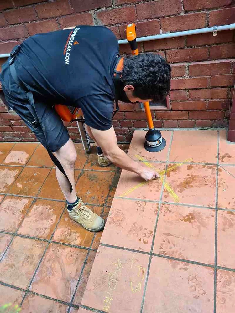 Technician with an acoustic microphone listening for a leak under paving