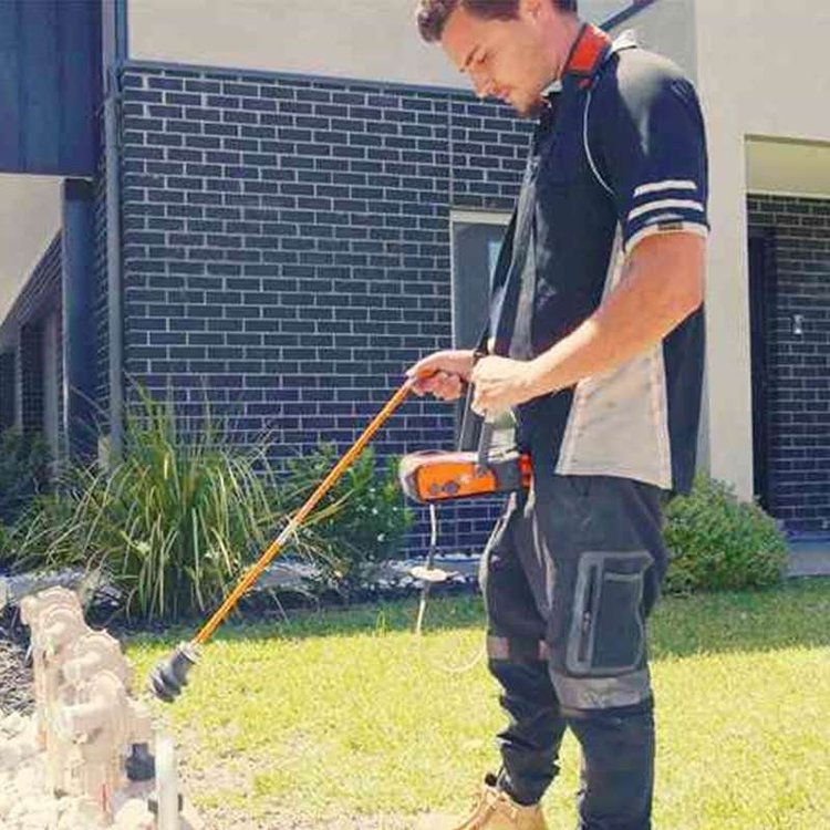 Technician with an acoustic microphone listening for an underground leak