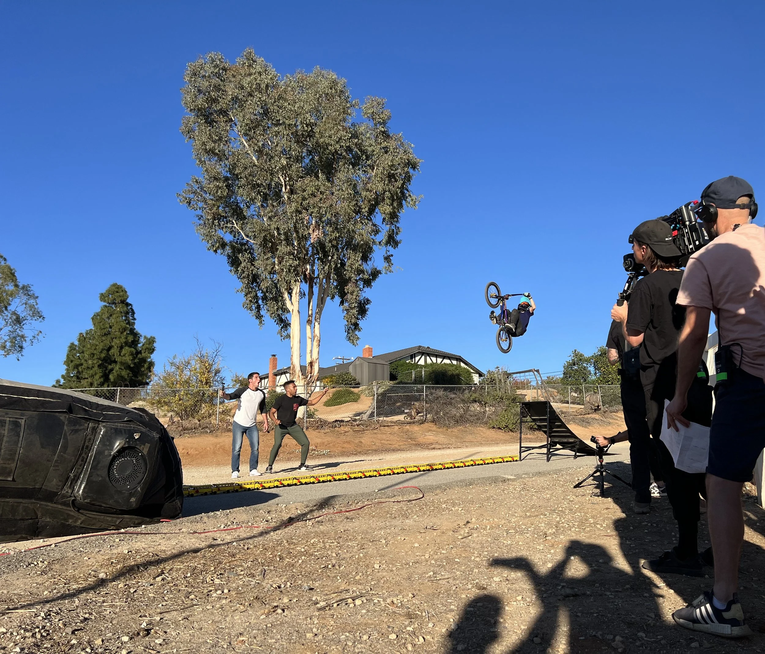 a 12-year old professional BMX rider flies off a ramp executing a backflip while the two hosts of Rebrickulous look on in excitement, in the foreground our production team is filming