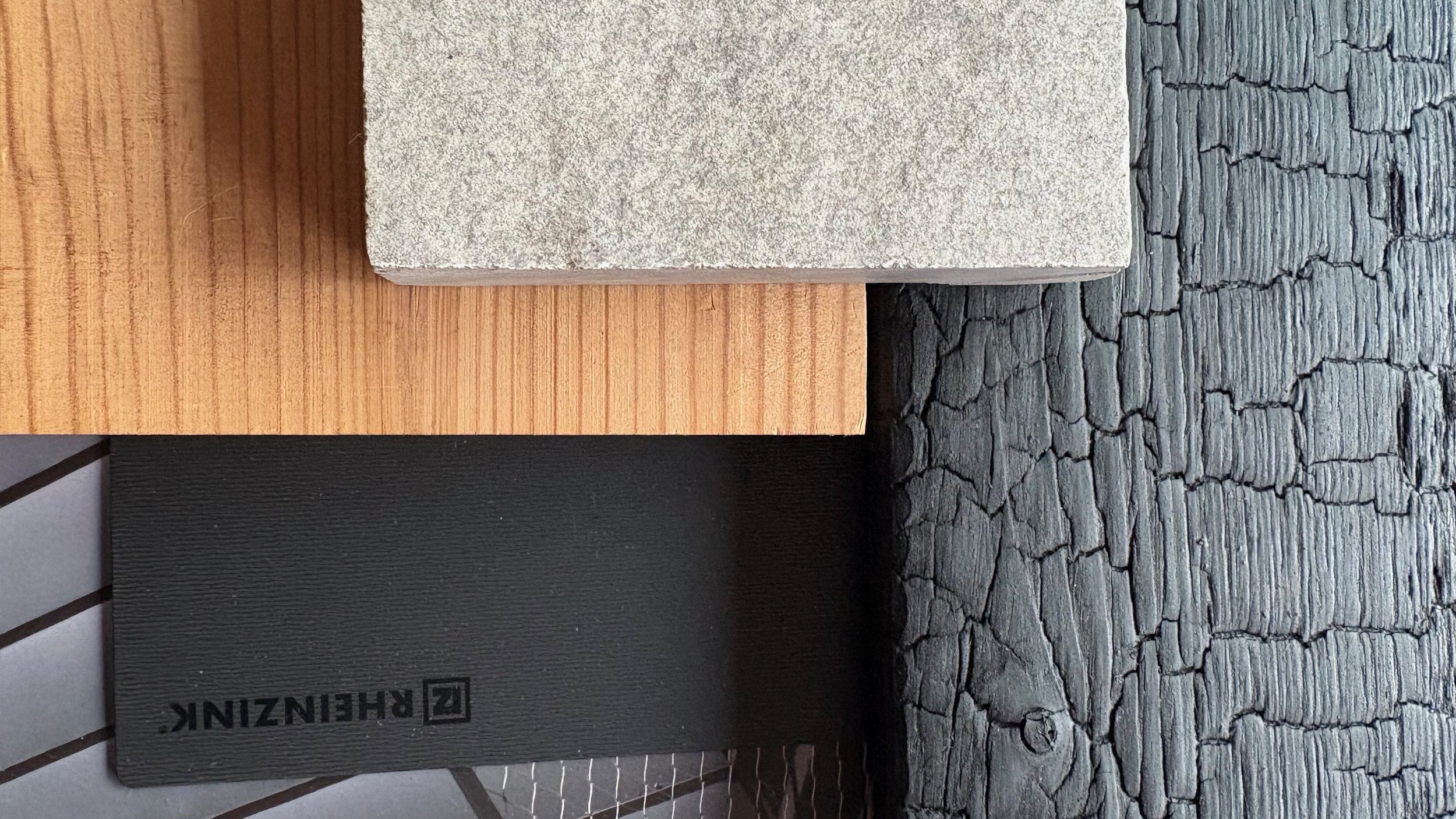 Close-up of five different textured tile samples arranged vertically, including wood, concrete, black painted, and cracked gray surface.