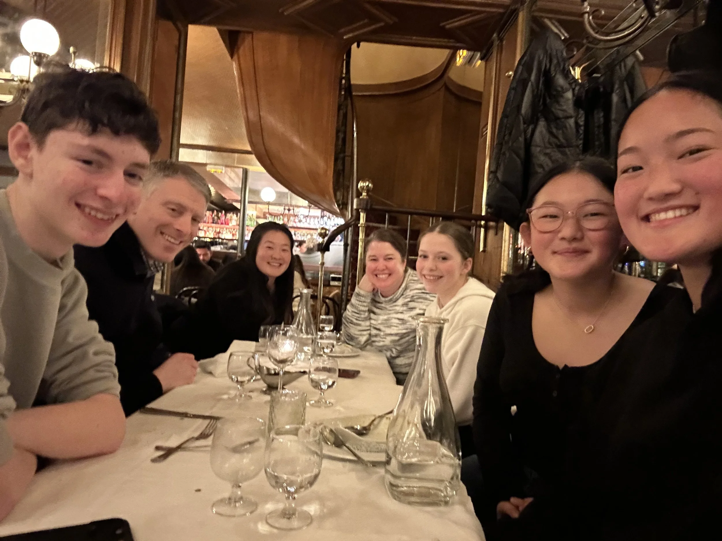 Friends gathering for dinner in Paris, France. White tablecloths and glasses cover the tables.