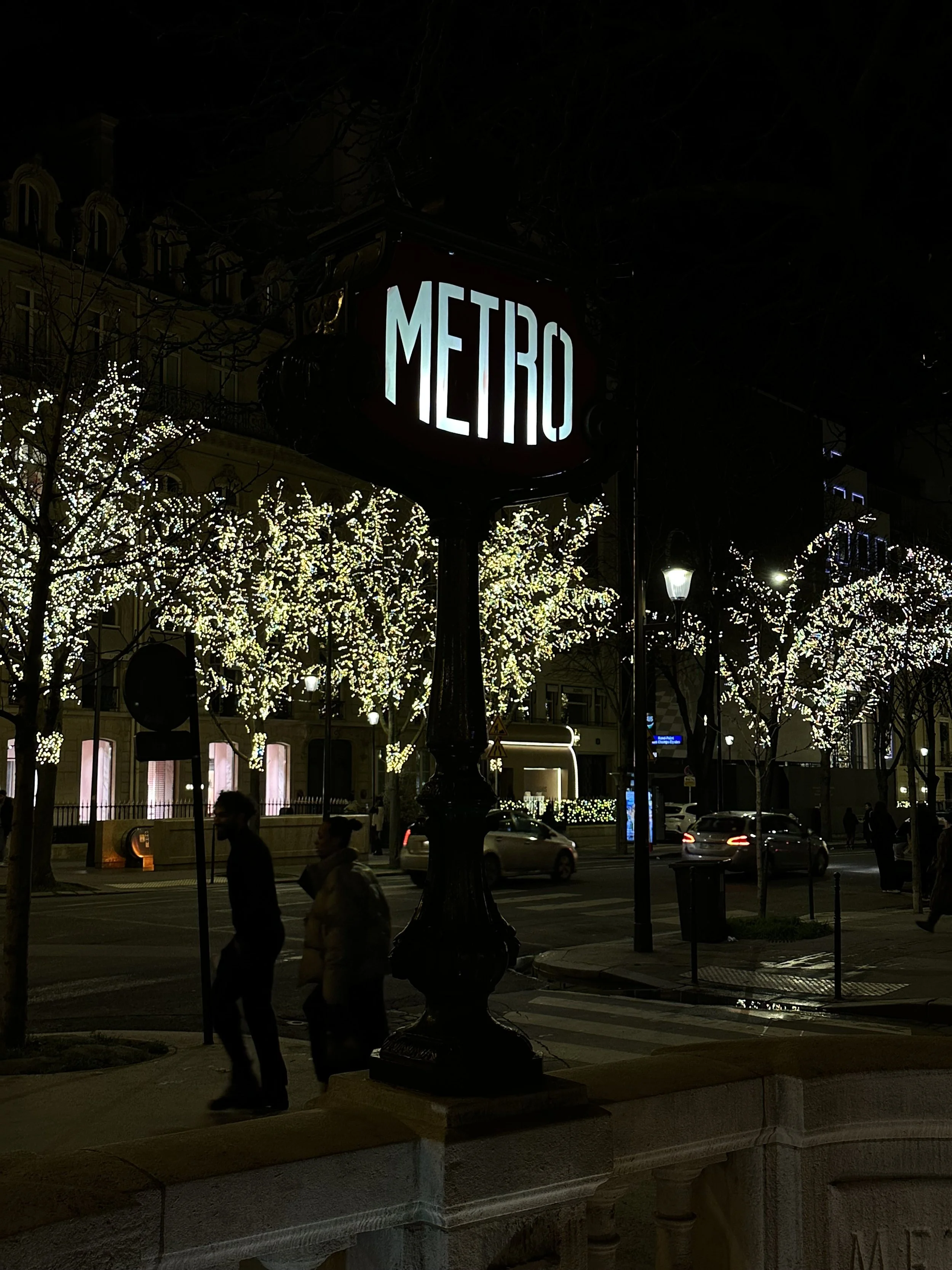 A Metro stop sign lit up at night in Paris
