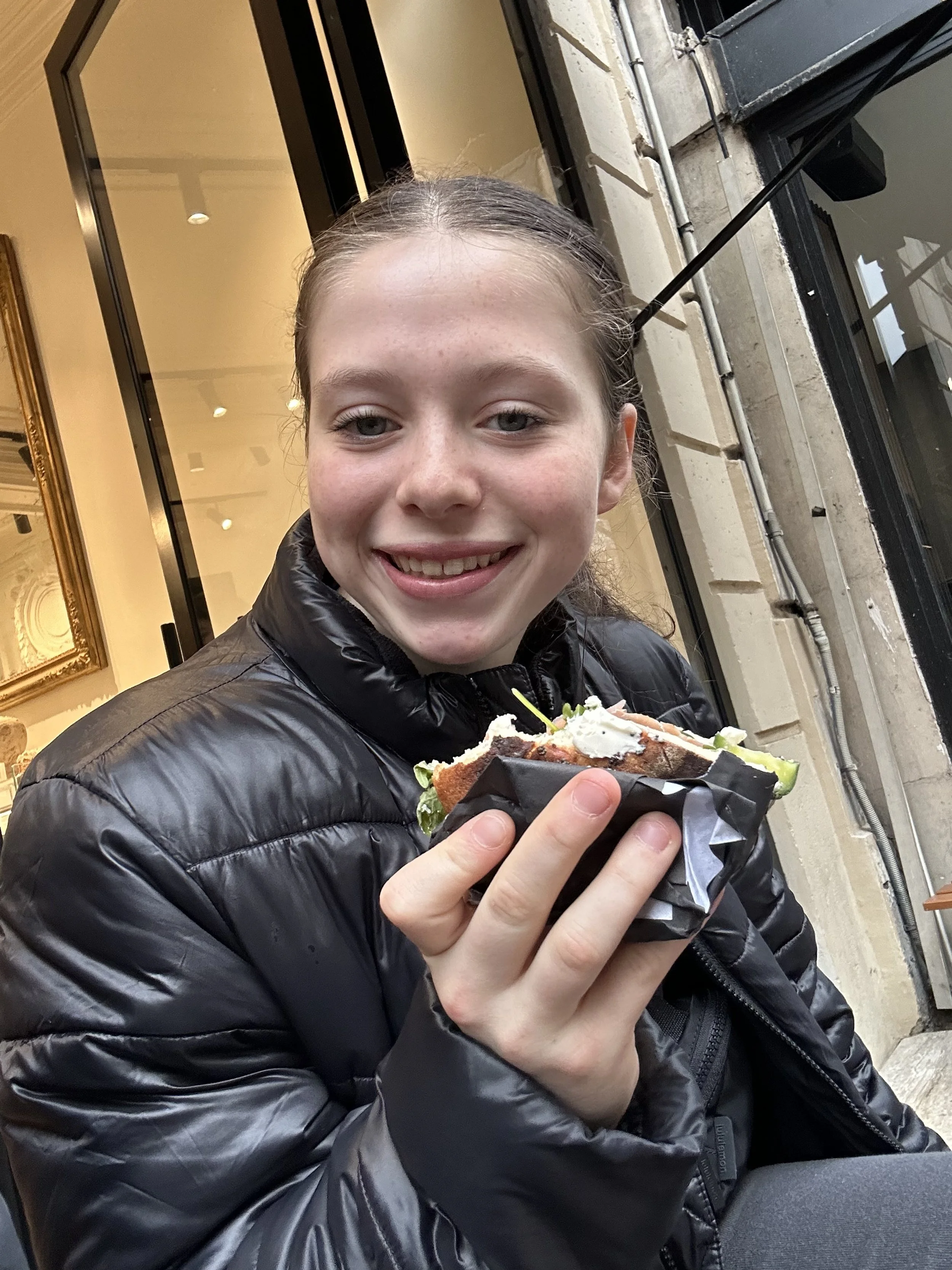 Teenage girl, who must eat gluten free, enjoying a gluten free bagel in Paris