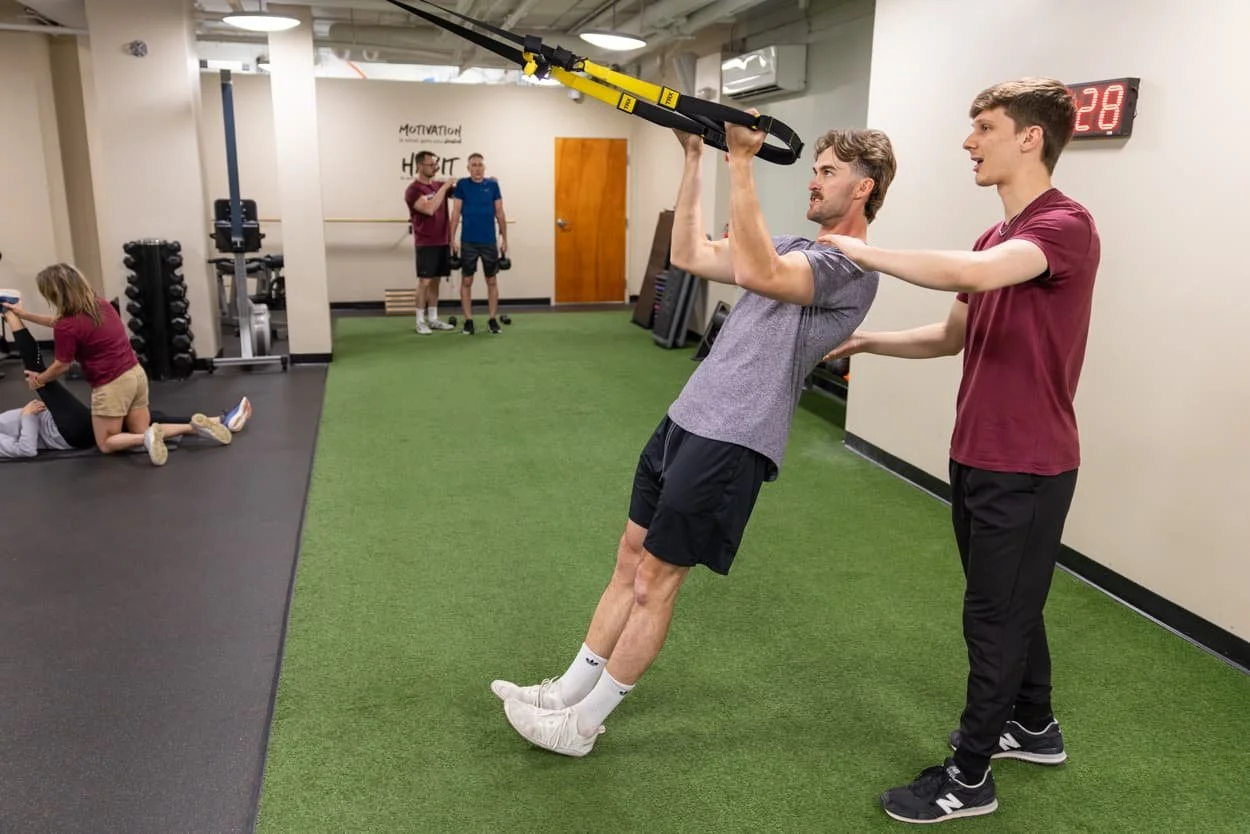 Body Soul trainer guiding a client through a TRX suspension training exercise at the Providence fitness studio.