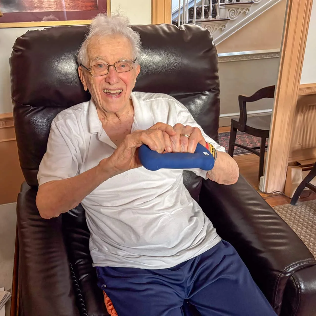 Older adult performing seated strength exercises during an in-home wellness session.