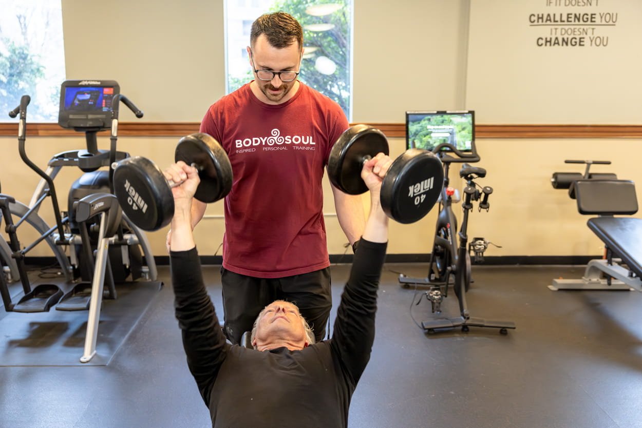 Body Soul personal trainer coaching a client through a dumbbell strength training exercise at the Providence fitness studio.