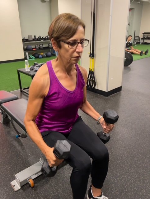 Woman performing seated dumbbell strength training at Body Soul Training gym