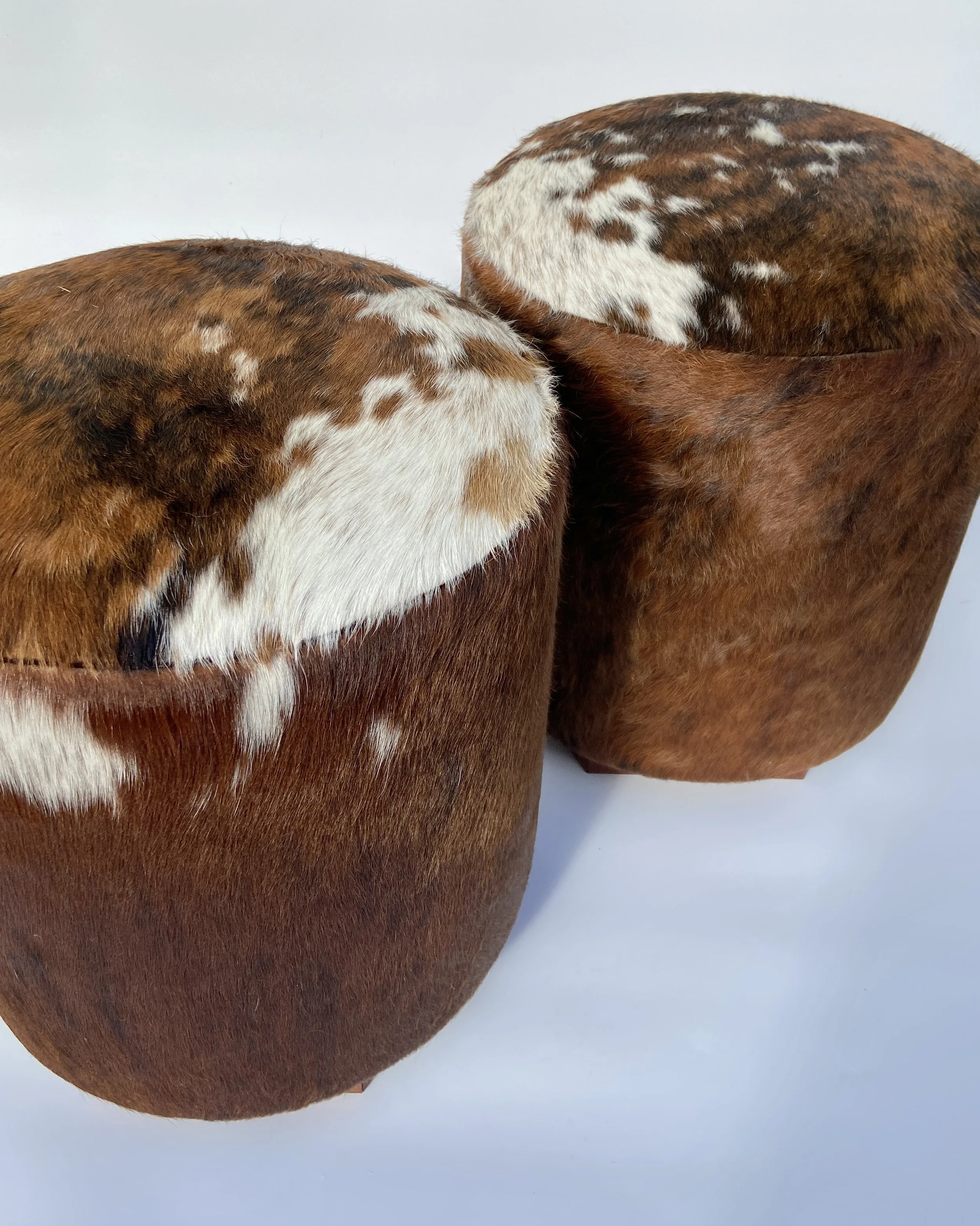 Pair of rustic cowboy-style leather and animal hide boots on a white surface.