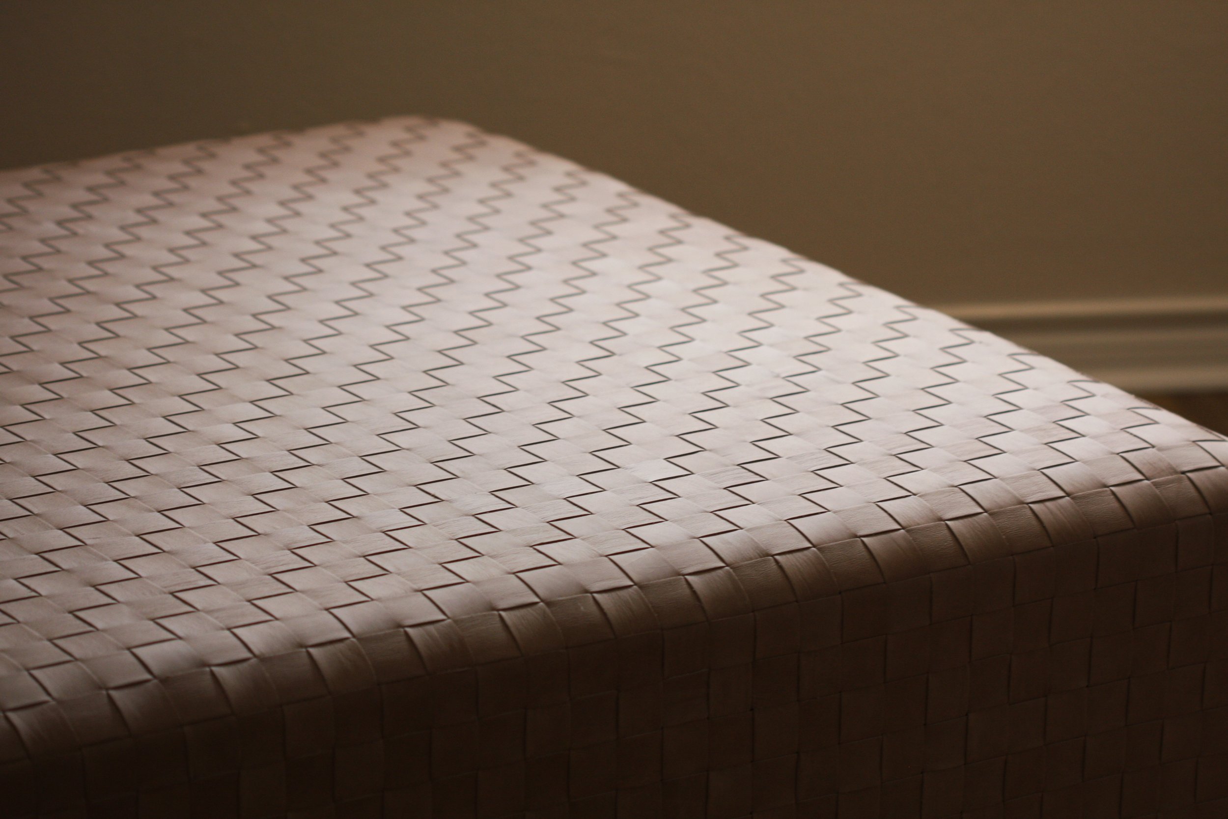 Close-up of a woven white mat with a zigzag pattern, partially in shadow.