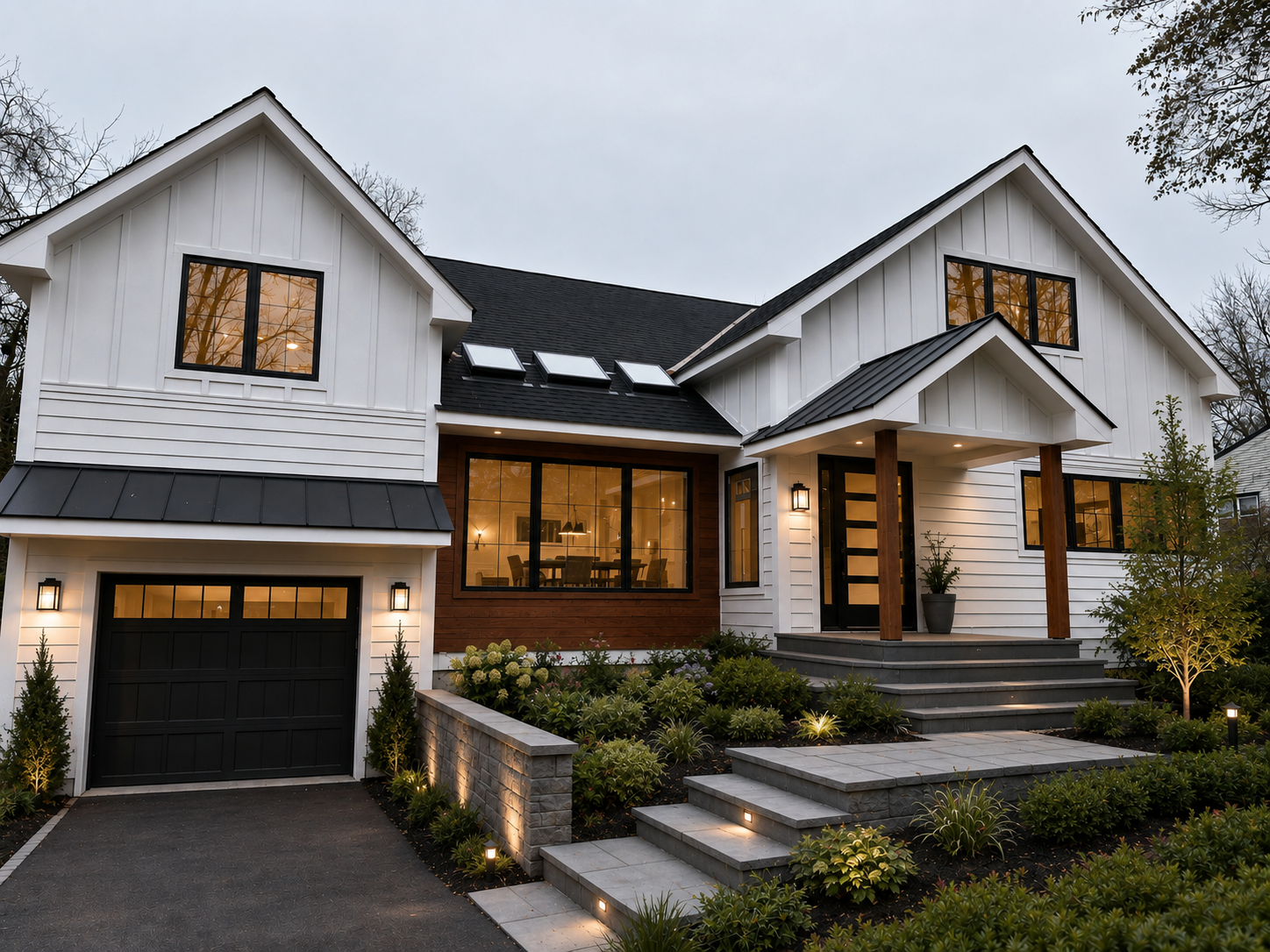 Modern white house with black roof and large windows, landscaped front yard with steps and lighting, at dusk.