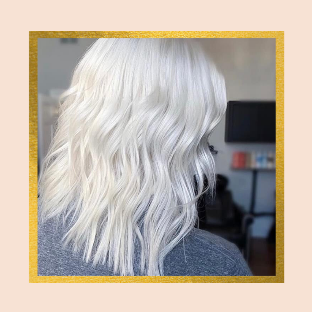 Woman with platinum blonde wavy hair in a salon setting.