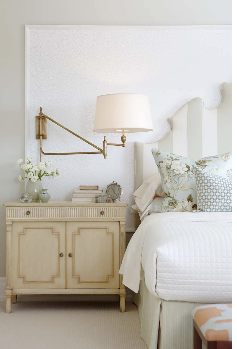 Transitional bedroom with upholstered headboard, brass swing arm sconce, neutral palette, and classic nightstand creating a soft and timeless space.