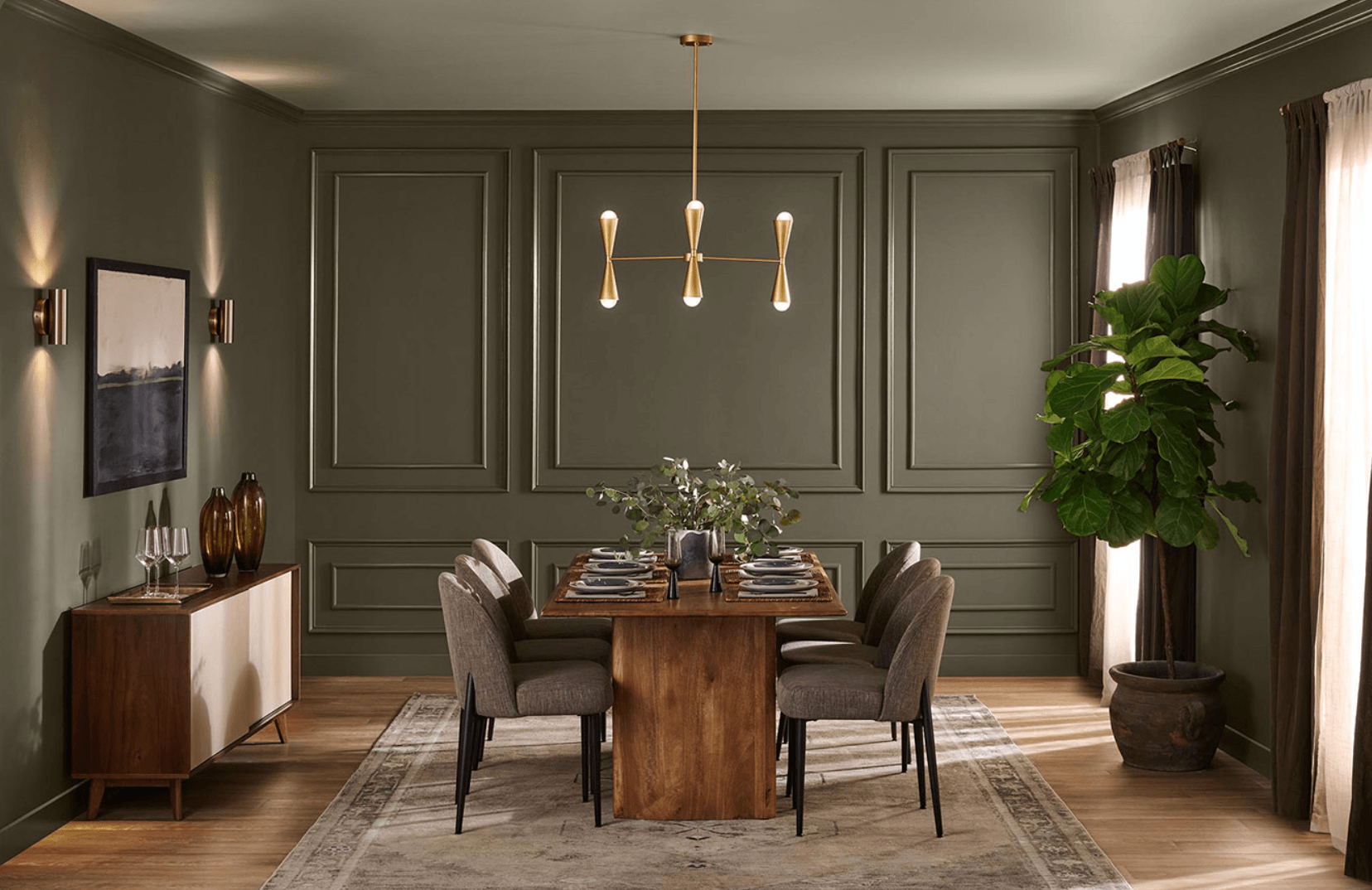 Sophisticated dining room featuring Behr Grounded T27-01, the 2027 Colour of the Year, with olive green walls, decorative moulding, warm wood furniture, and brass lighting.