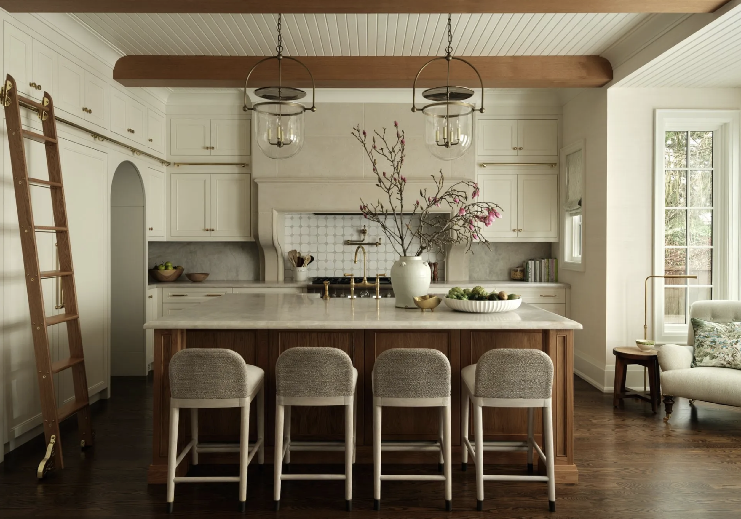 Light-filled transitional Kitchen featuring an island light brown base and white/ cream quartz, sculptural flush mount lighting, light cream chairs, and soft neutral finishes that create a collected, cohesive space for the winter season
