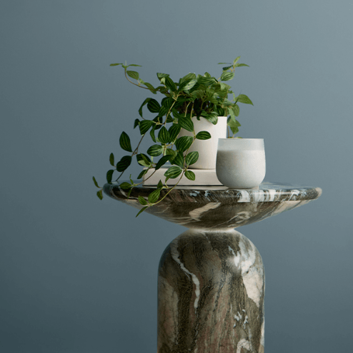 Valspar Cottage Door V138-4, the 2027 Colour of the Year, shown as a calming blue-grey backdrop for a sculptural marble pedestal and greenery.