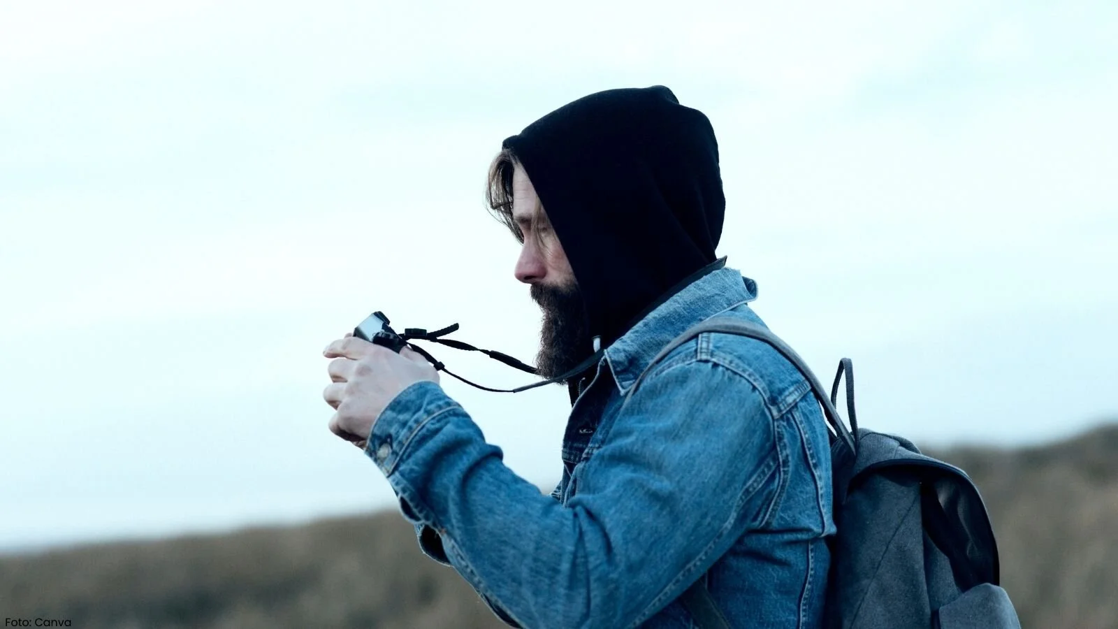 Mann med hettejakke som fotograferer i friluft. Foto: John Shepherd / Canva