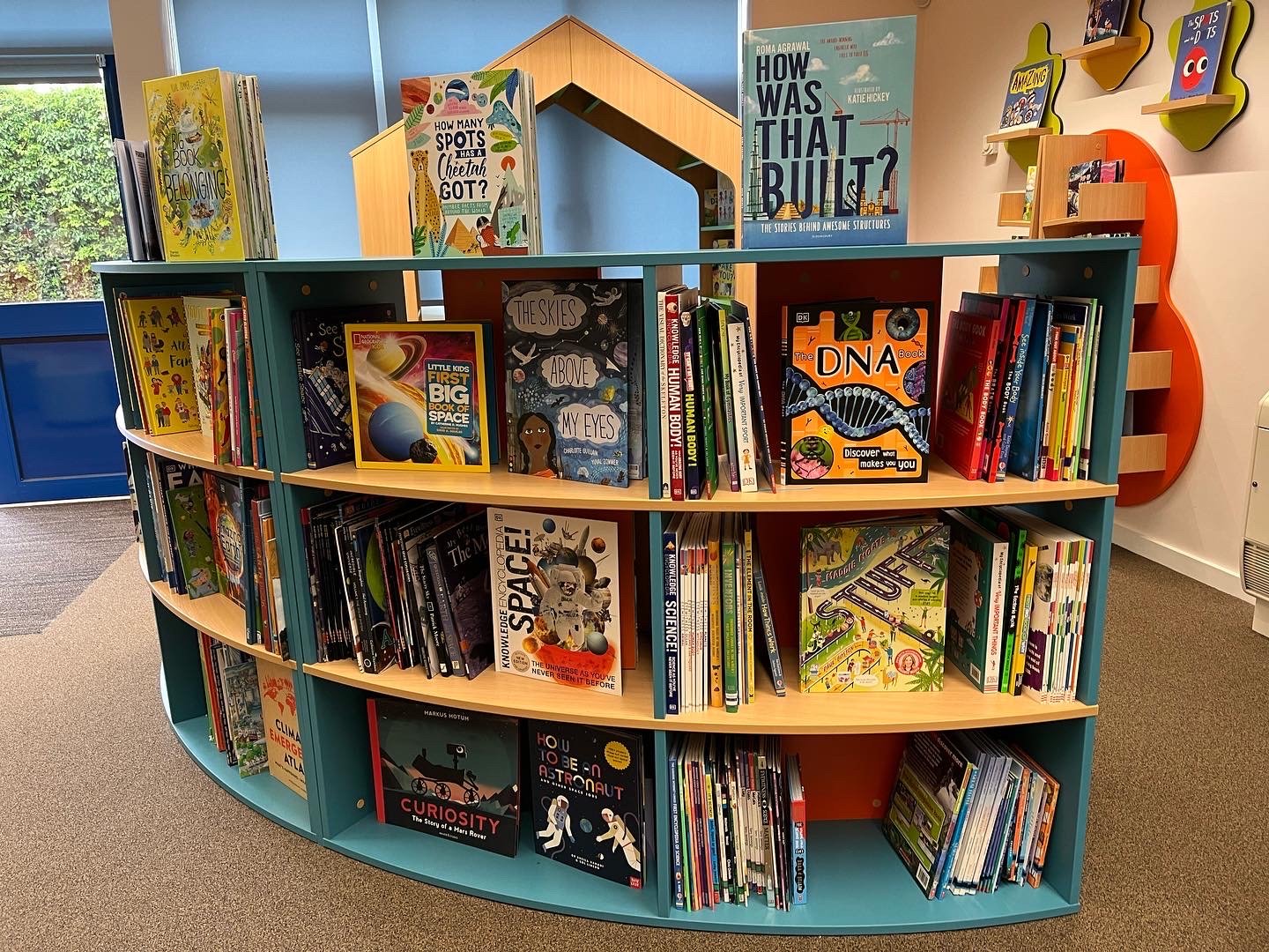 Children's section in a library with books on science, history, and nature displayed on shelves.