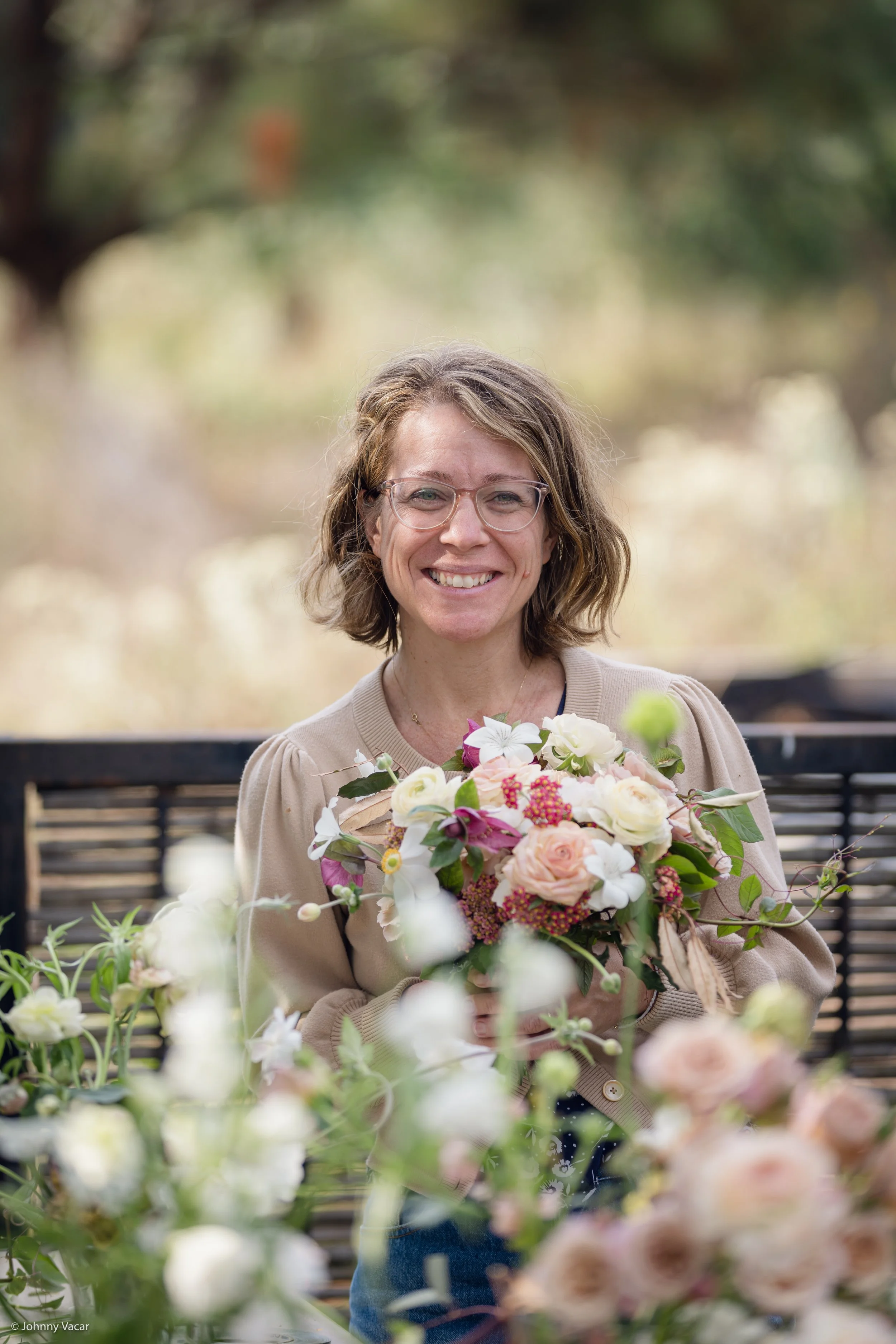 Josy Johnson, the florist in Austin,  holding a bouquet of flowers outdoors, smiling. Photo taken in Valle de Bravo