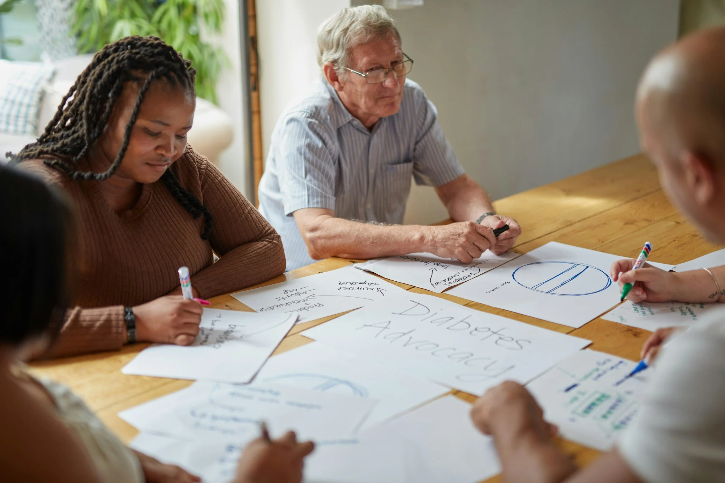A woman and a man sit next to each other, writing notes in a meeting