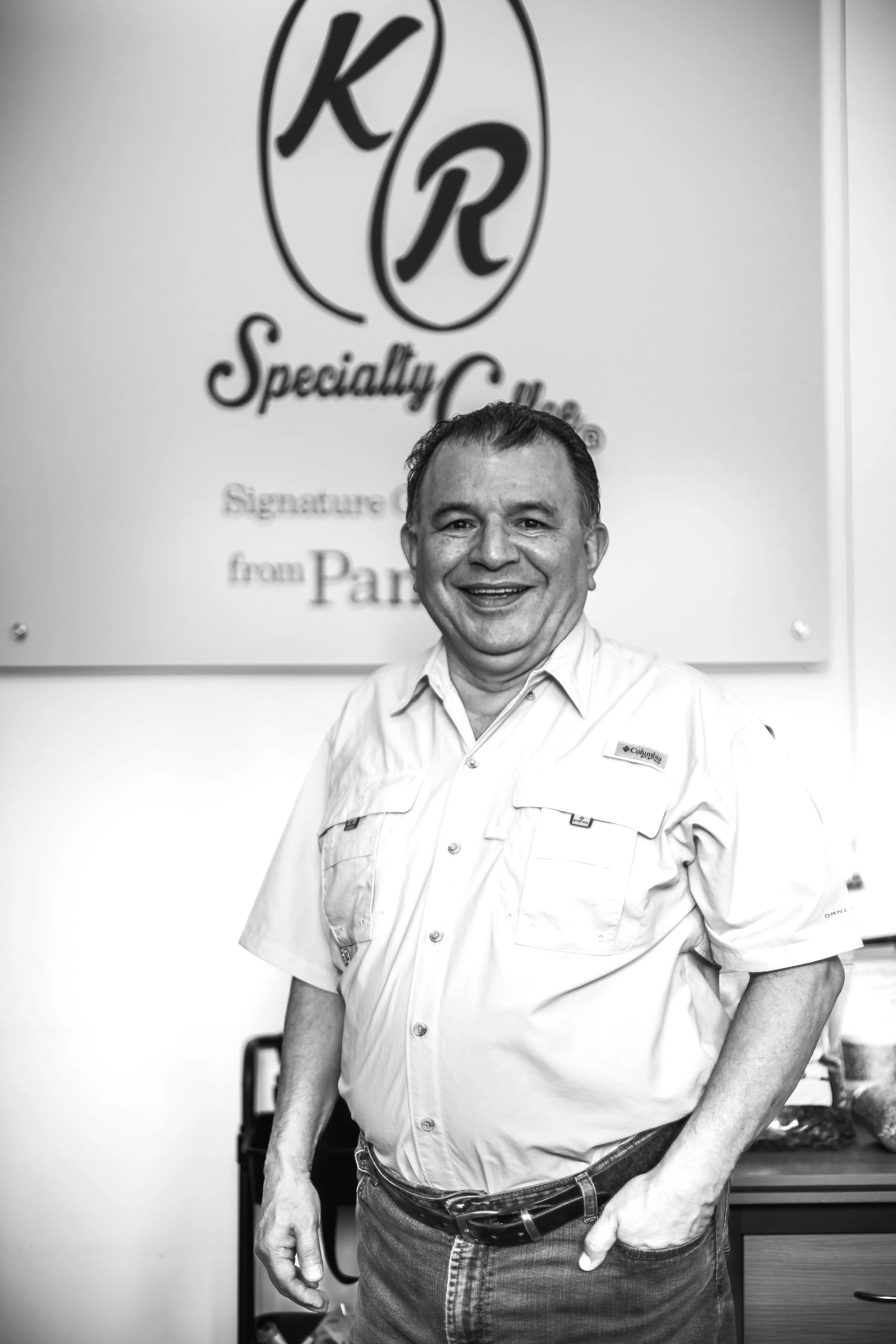 Black and White picture of Mr. Plinio Ruiz A with the K&R Specialty Coffee Sign in the background