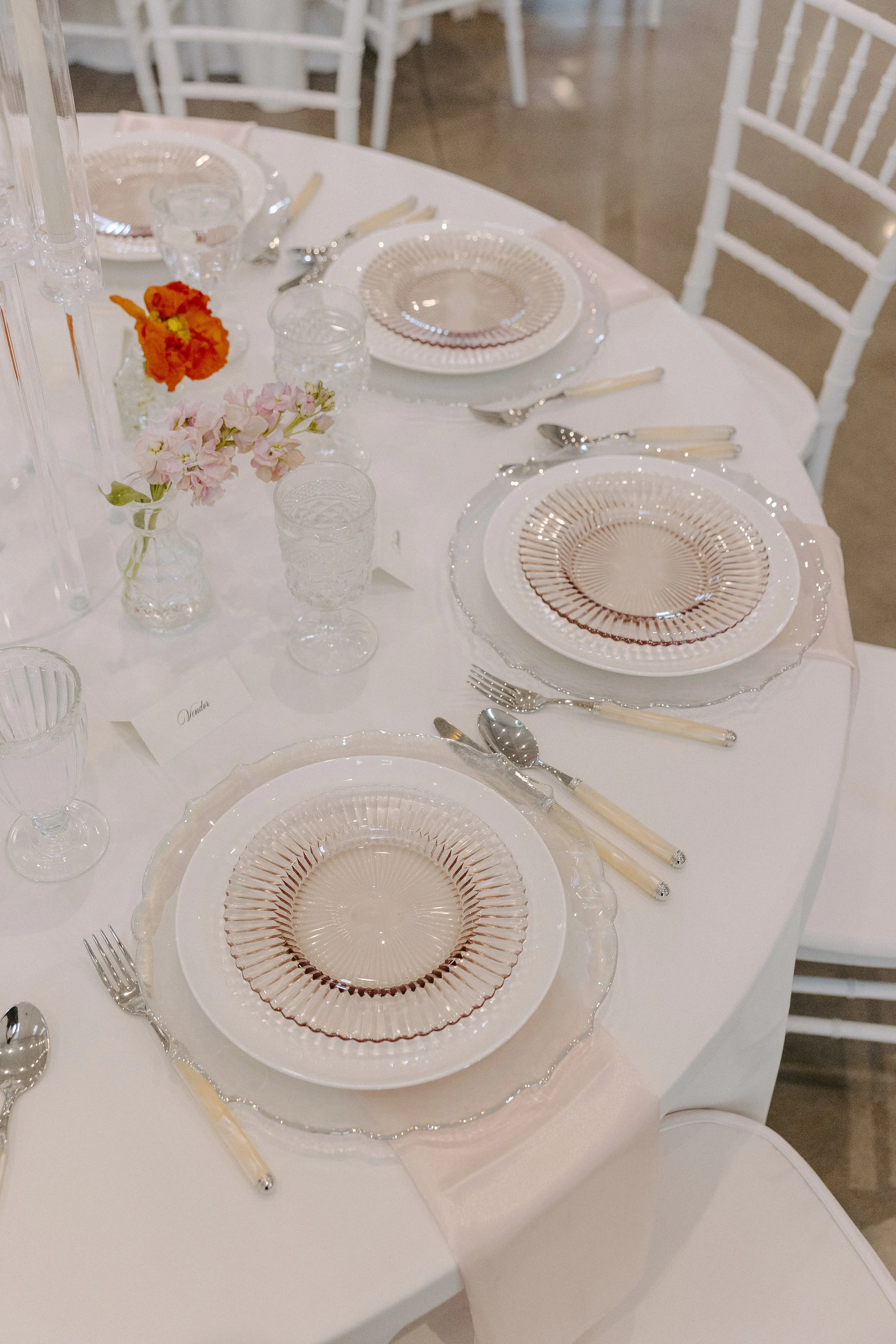 Refined wedding tablescape with blush glassware, pastel florals, and romantic details.