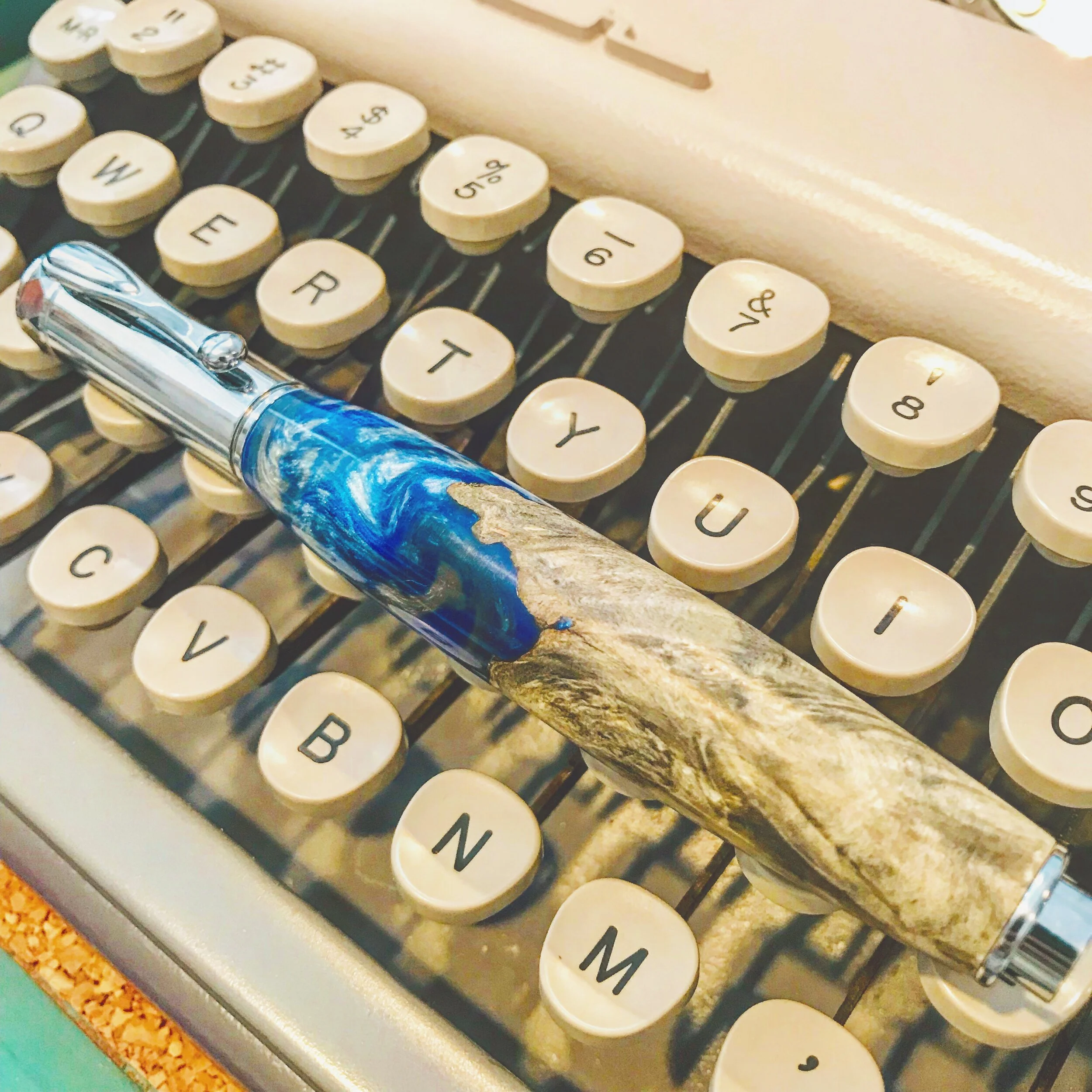 A silver zen pen in stabilized burl oak with blue acrylic inlay.
