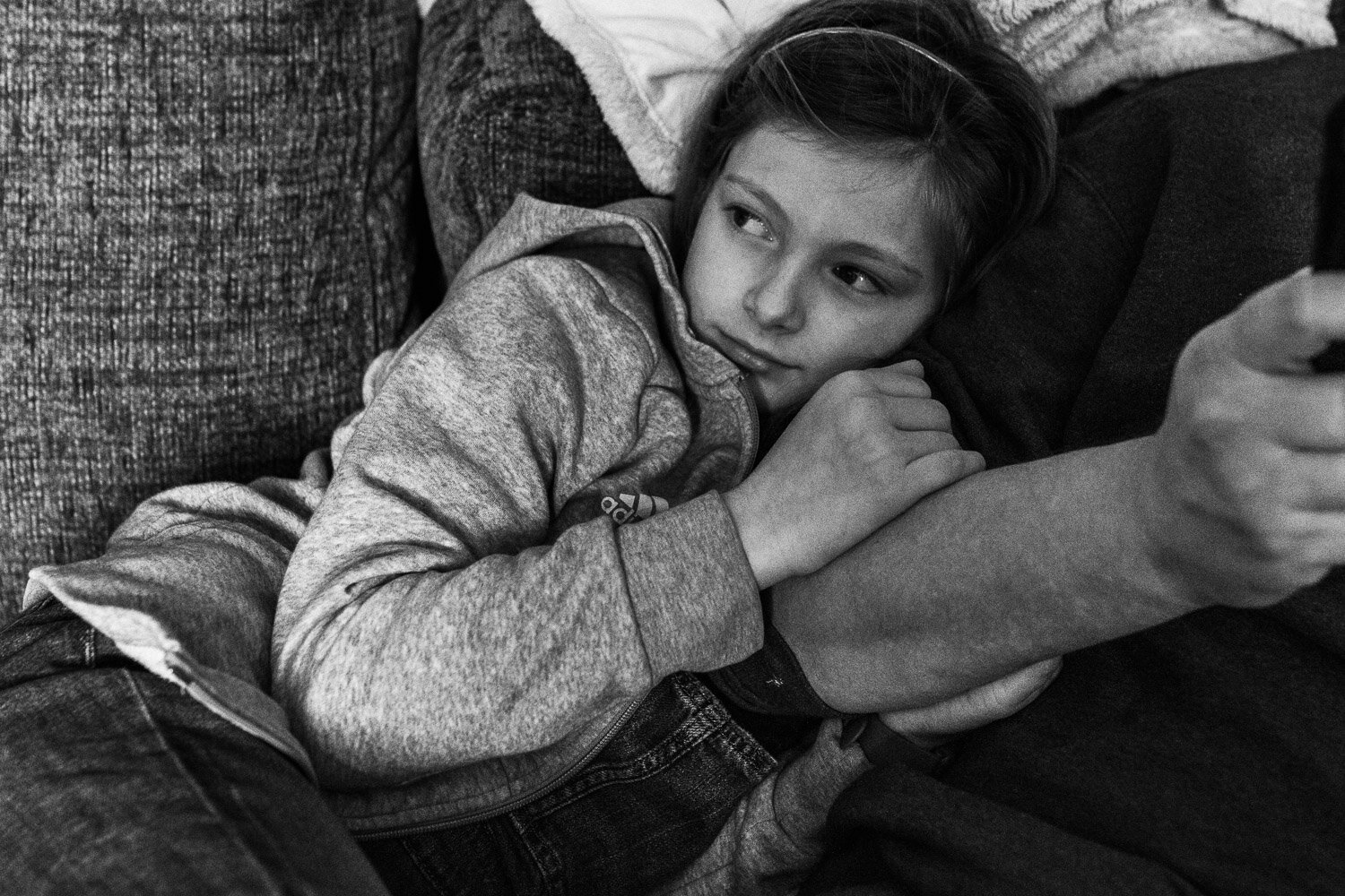 girl on couch holding on to father's arm looking off to the left black and white image
