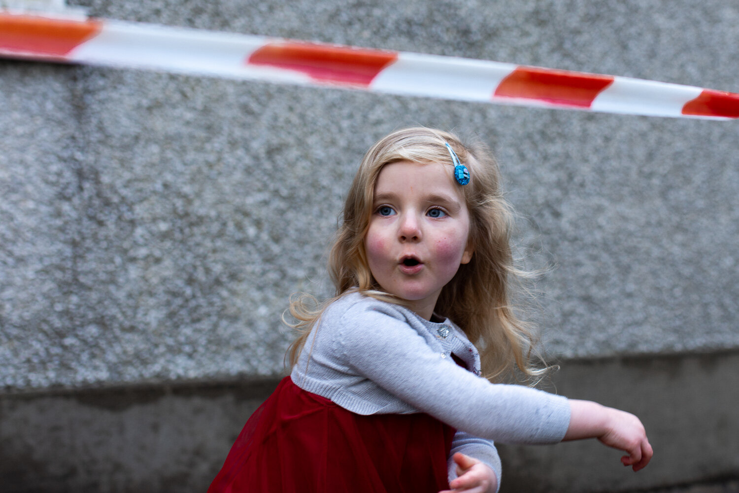 toddler girl wearing red and white standing under red white tape playing