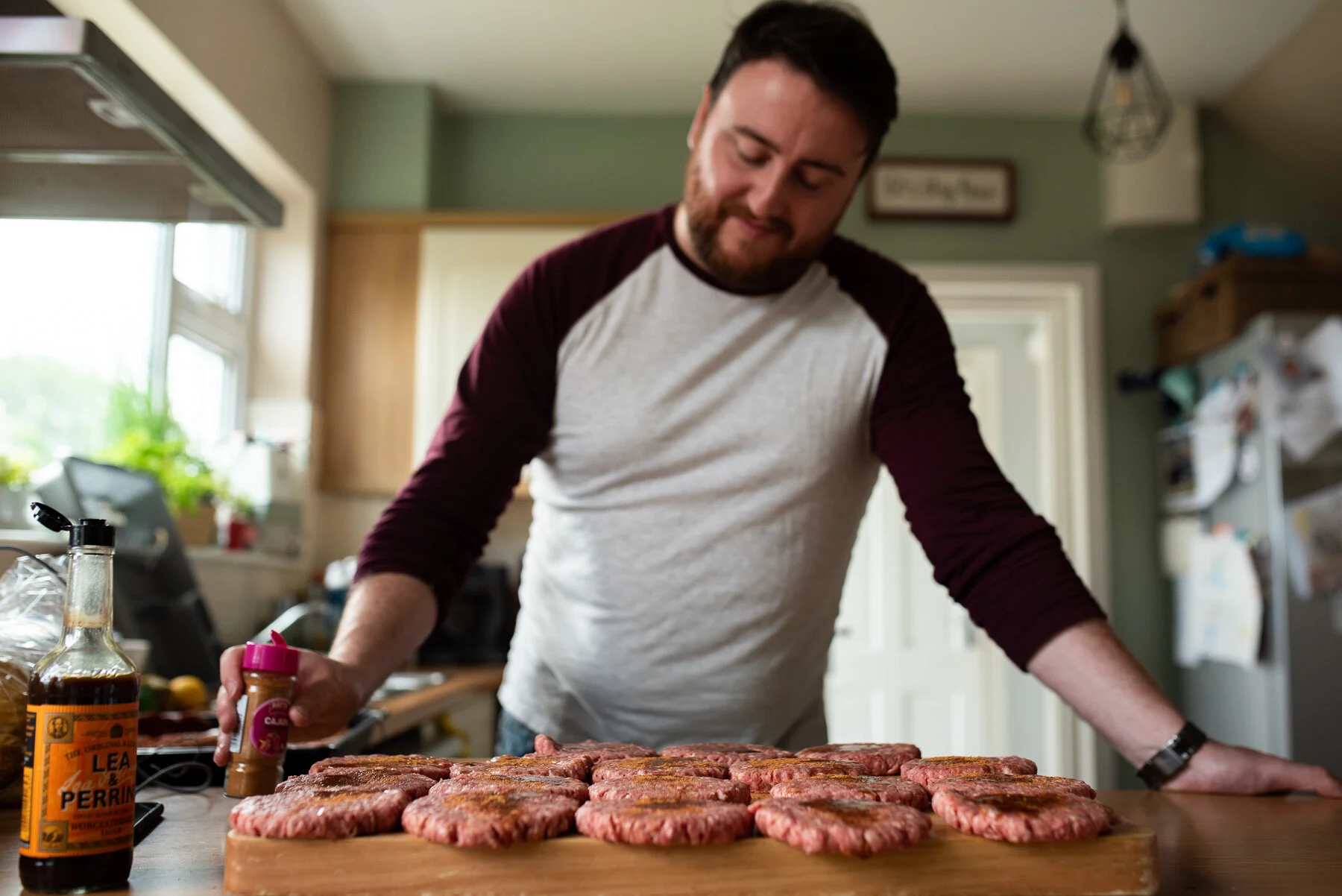 Man seasoning tray of hamburgers