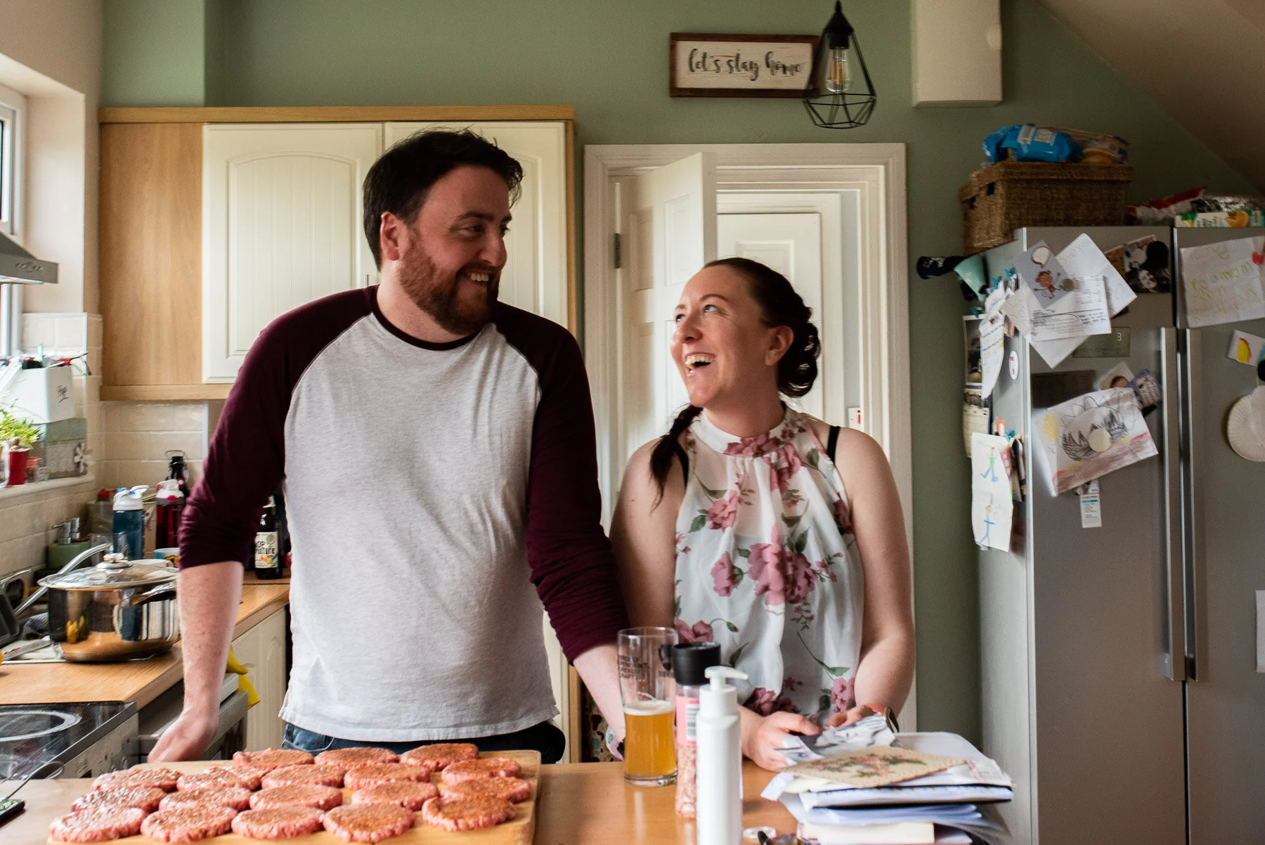 couple smiling at each other in front of uncooked hamburgers
