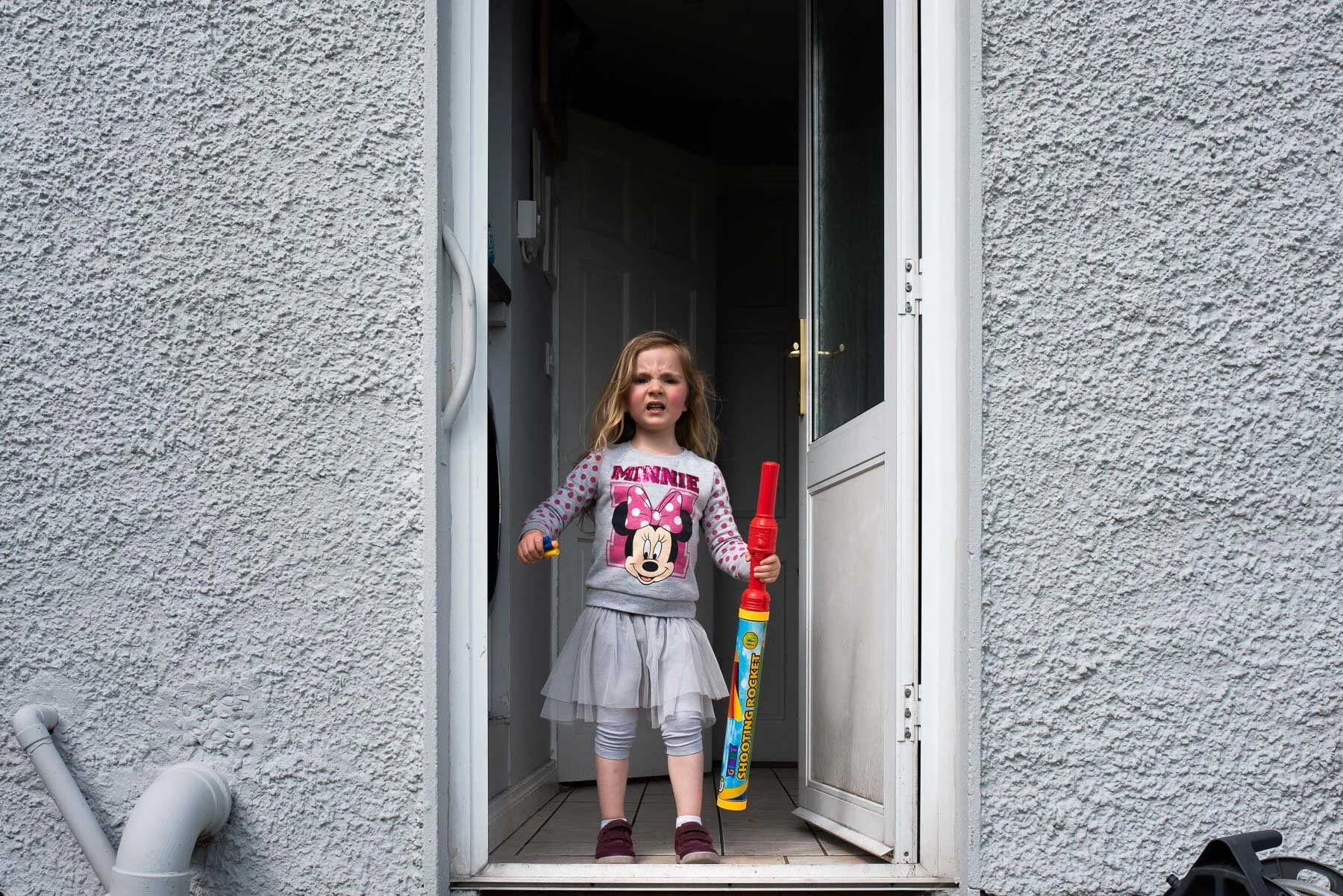 girl wearing grey tutu skirt standing in doorway going outside
