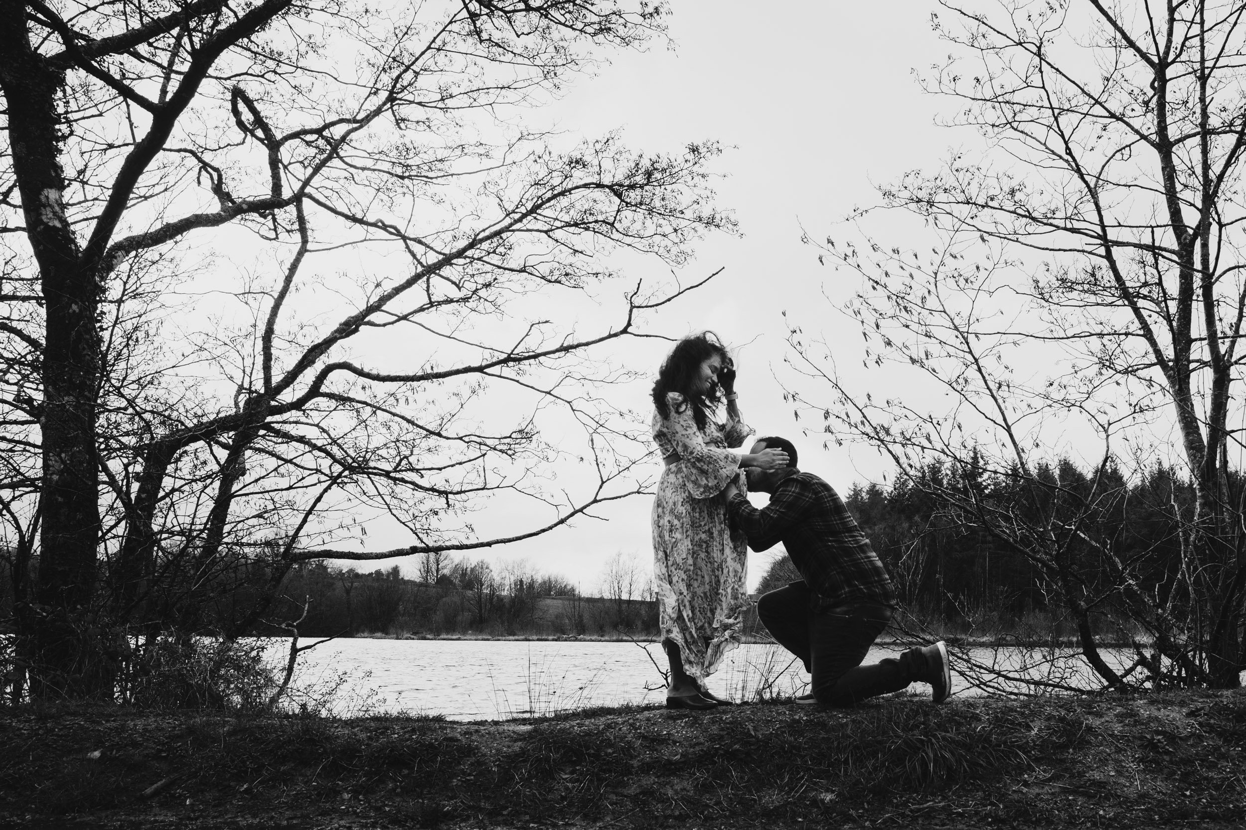 lake background husband kissing wife's belly rainy maternity shoot cratloe woods ireland maternity photographer ireland