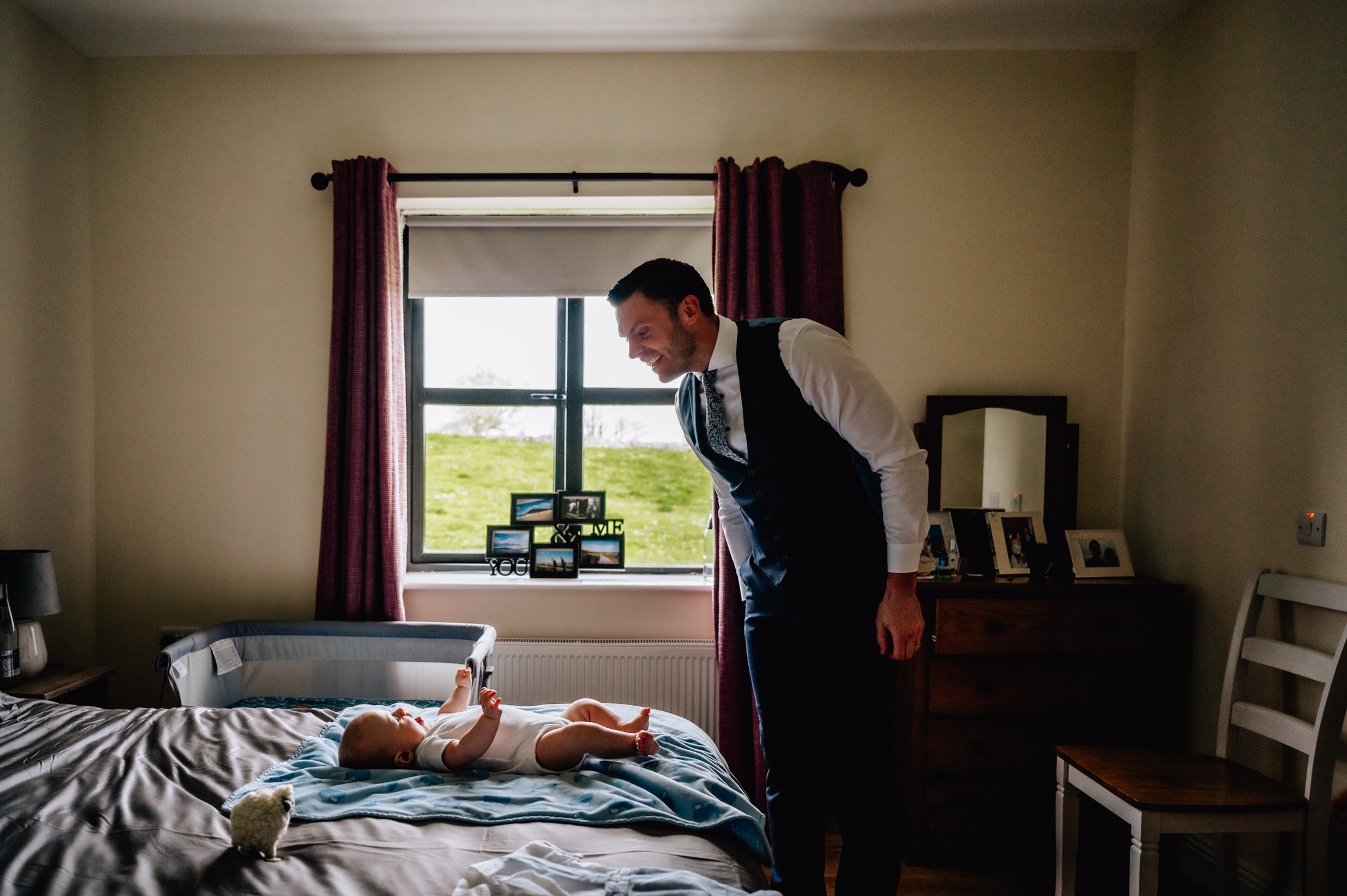 Dad looking on baby boy on bed christening photos limerick photographer