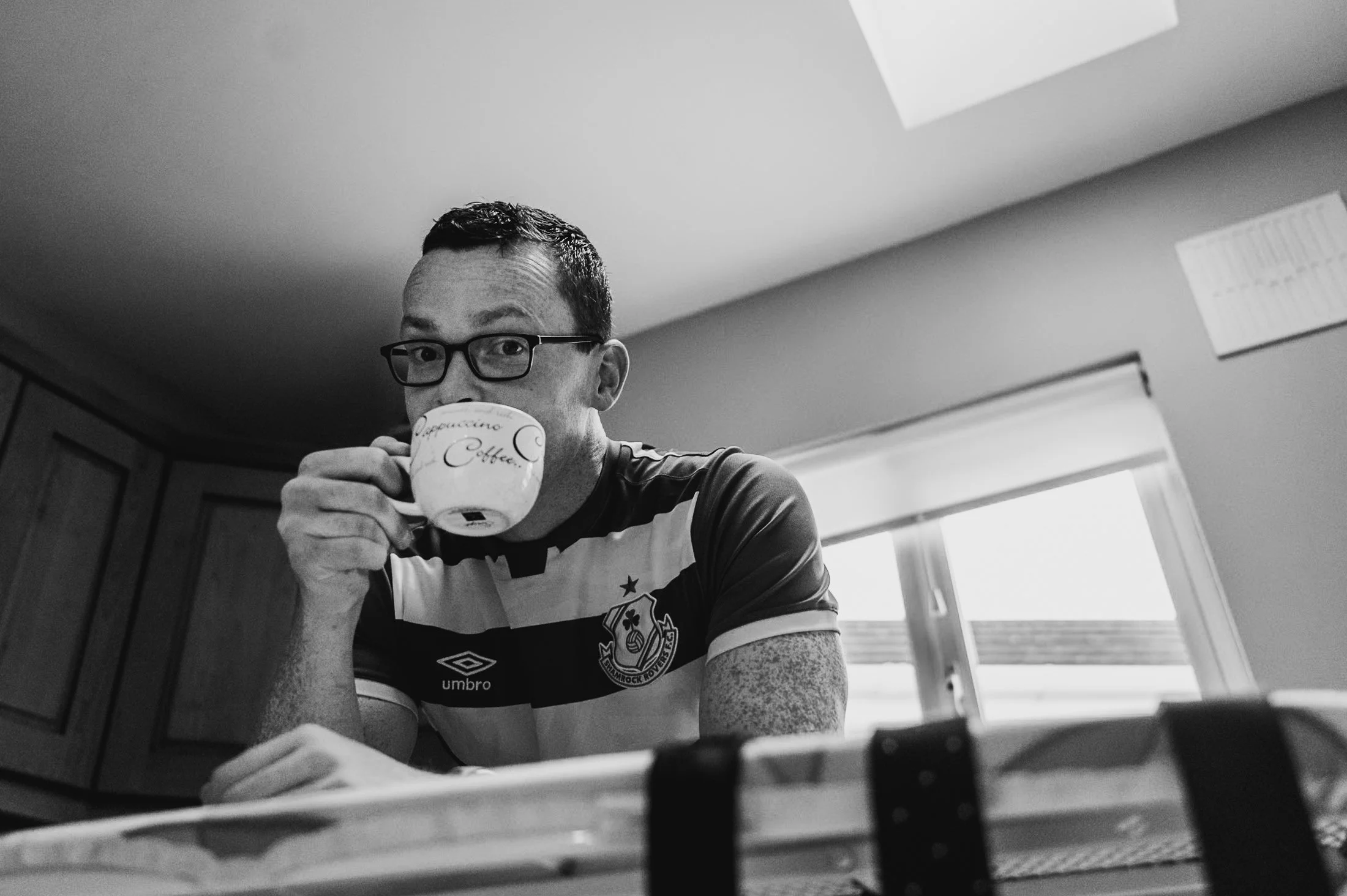 man drinking cup of coffee while ironing 