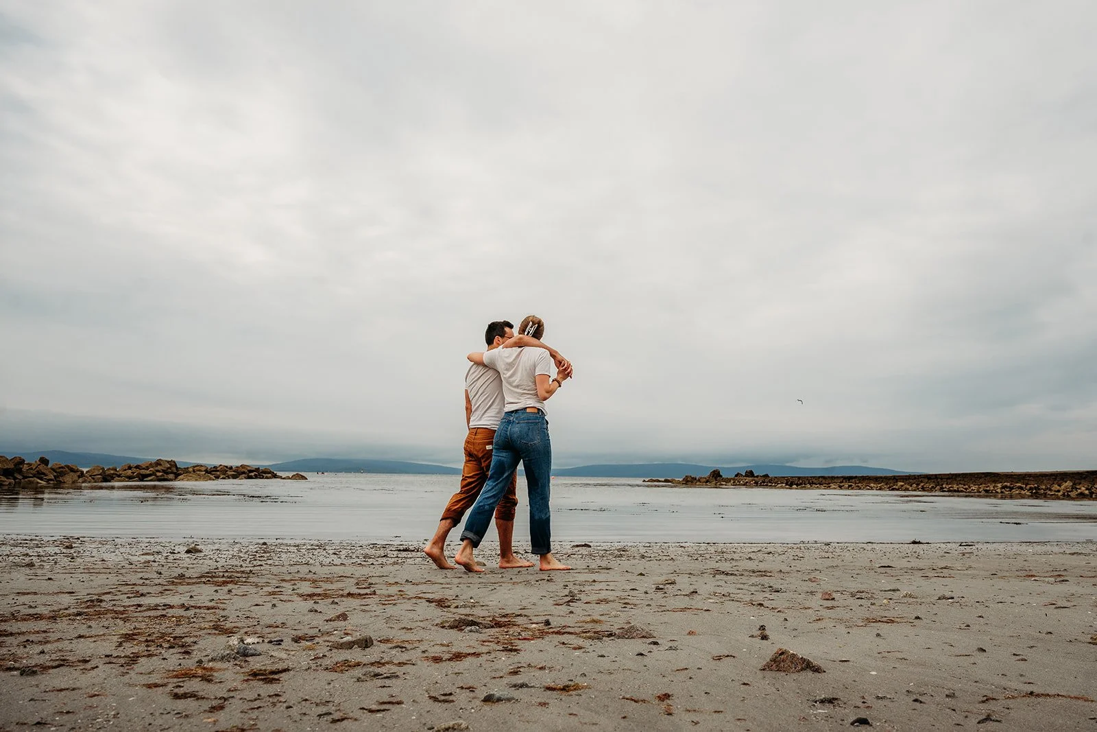 Galway Bay Hotel wedding photos Salthill promenade beach couple with arms around each other walking on the beach