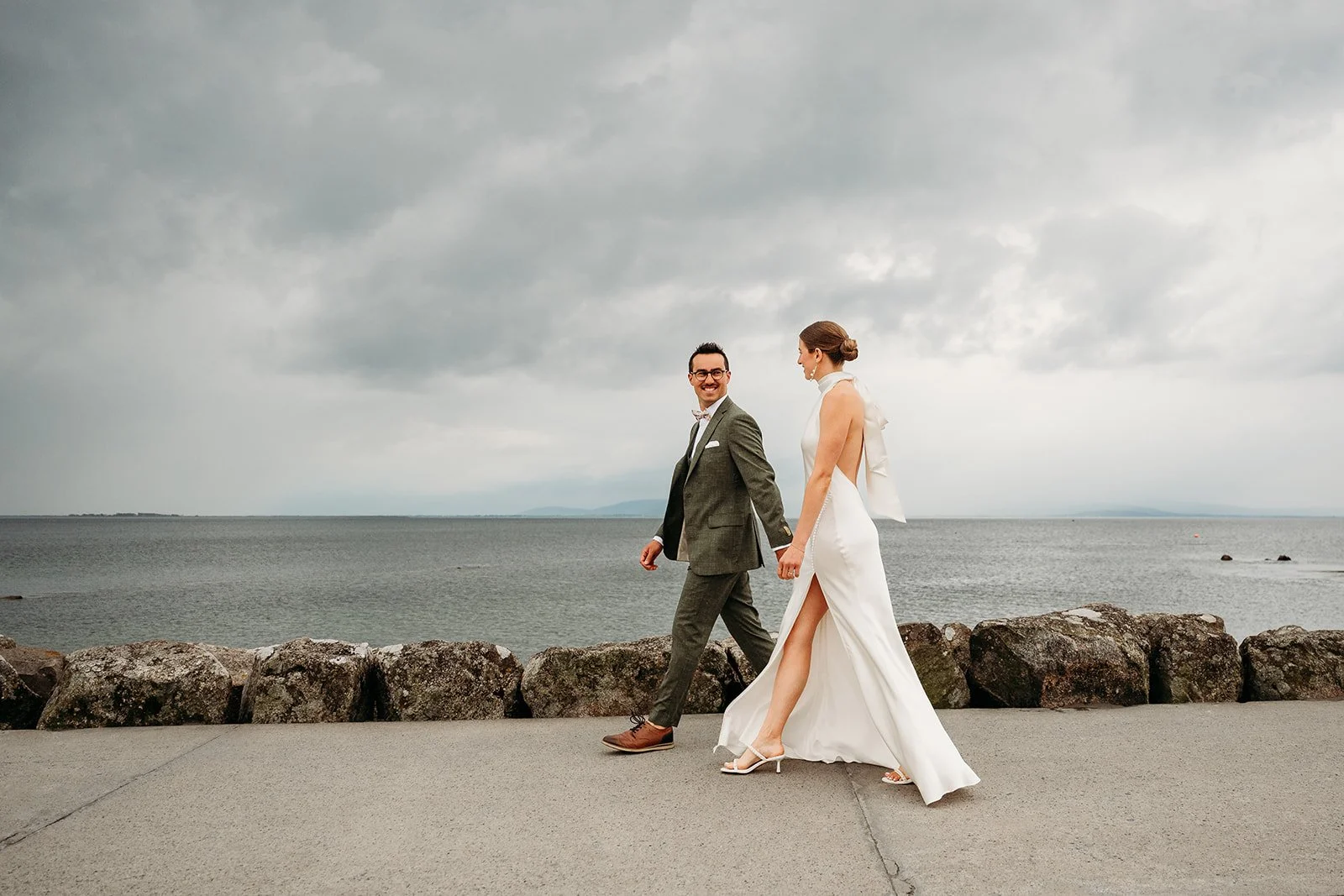 Galway Bay Hotel wedding photos Salthill promenade candid portrait couple walking groom in green suit bride in strapless dress