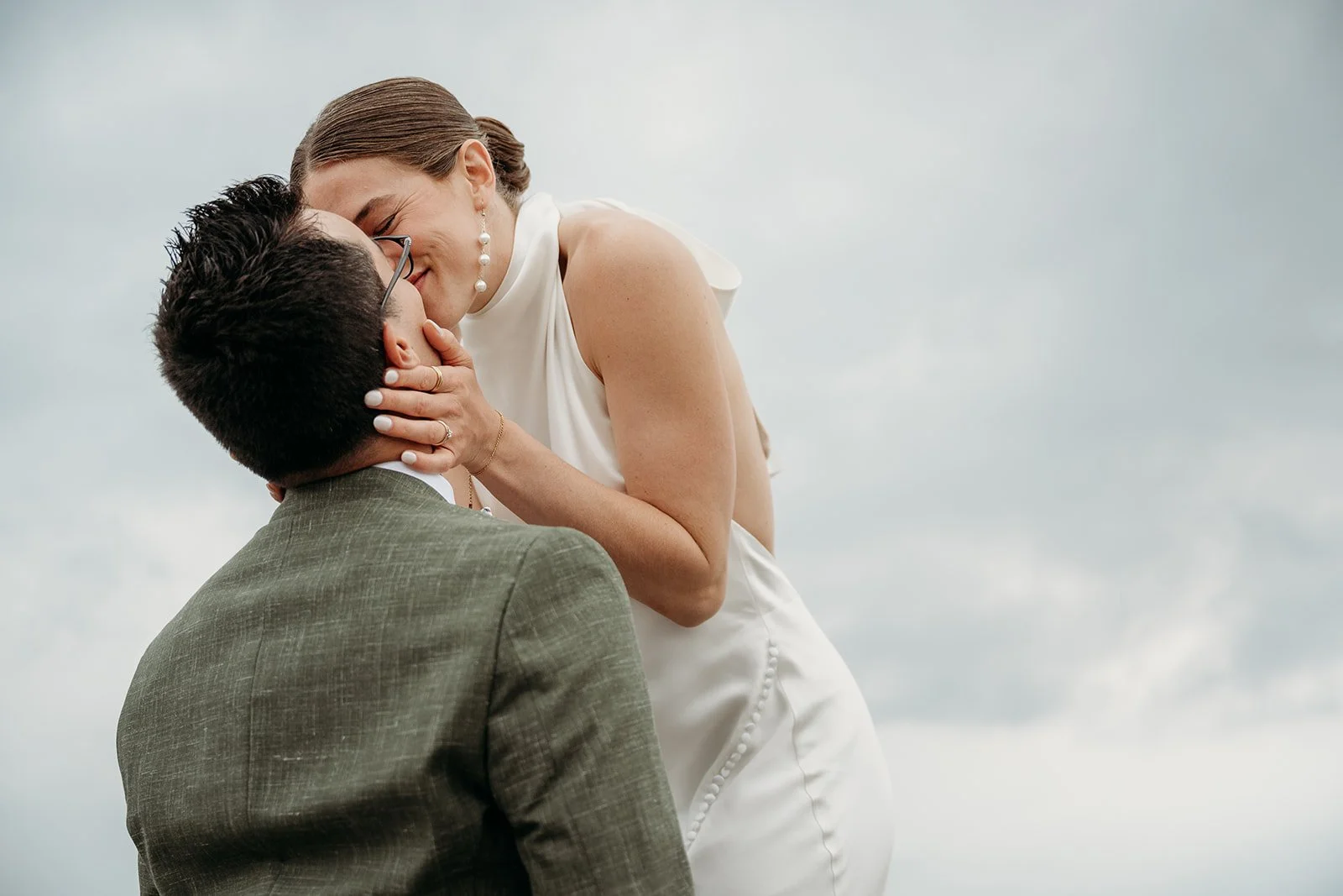 Galway Bay Hotel wedding photos Salthill promenade bride leaning down to kiss groom green suit