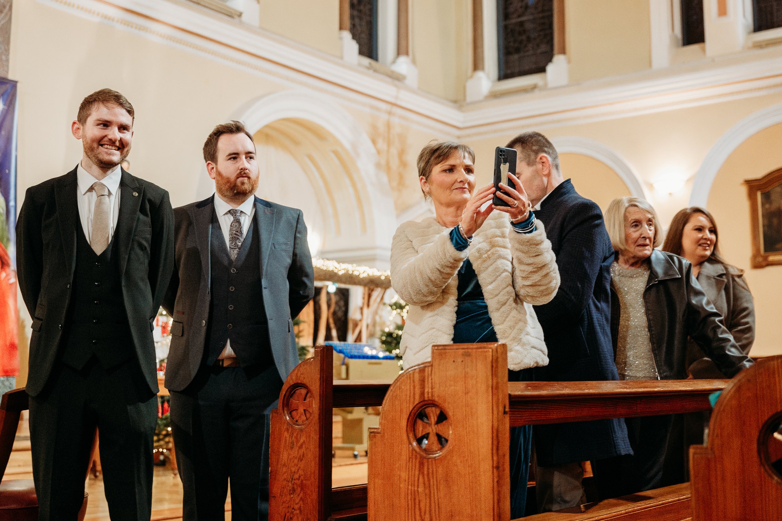 Wedding photo St Joseph's church Limerick city groom and best man waiting people taking phone photos