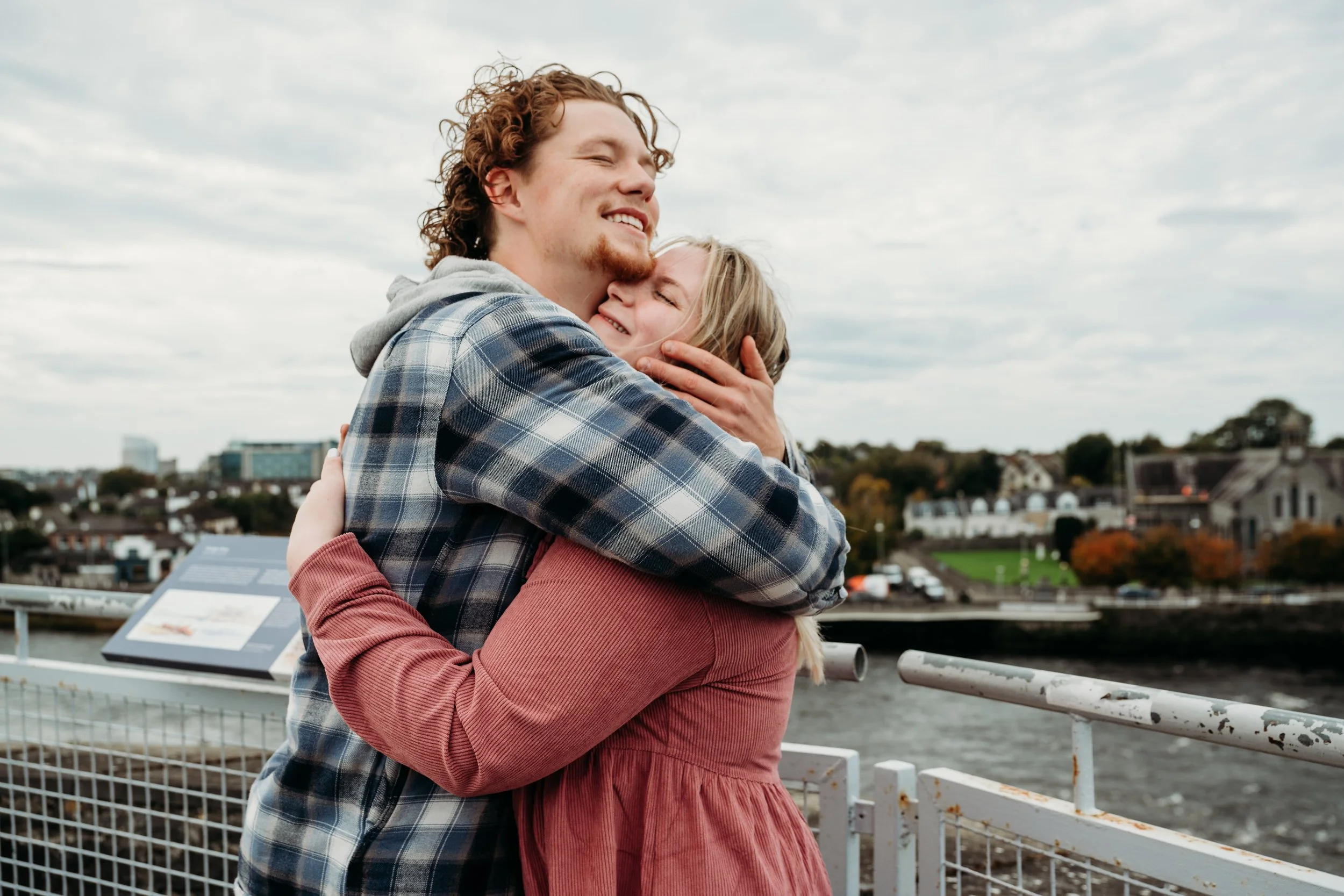 couple embraces on King John's castle Limerick city in background surprise proposal photographer Marie O'Mahony
