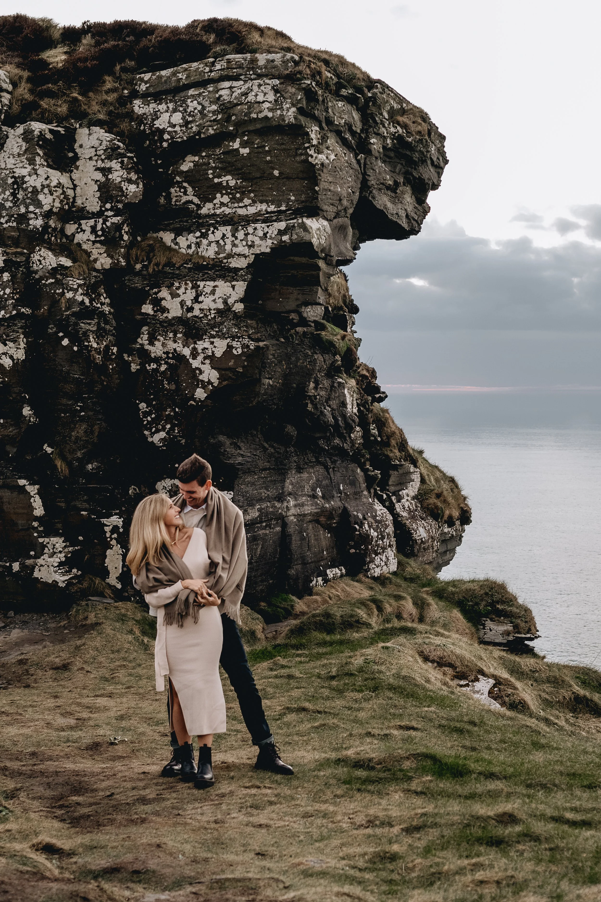 couple standing in front of sea cliff 