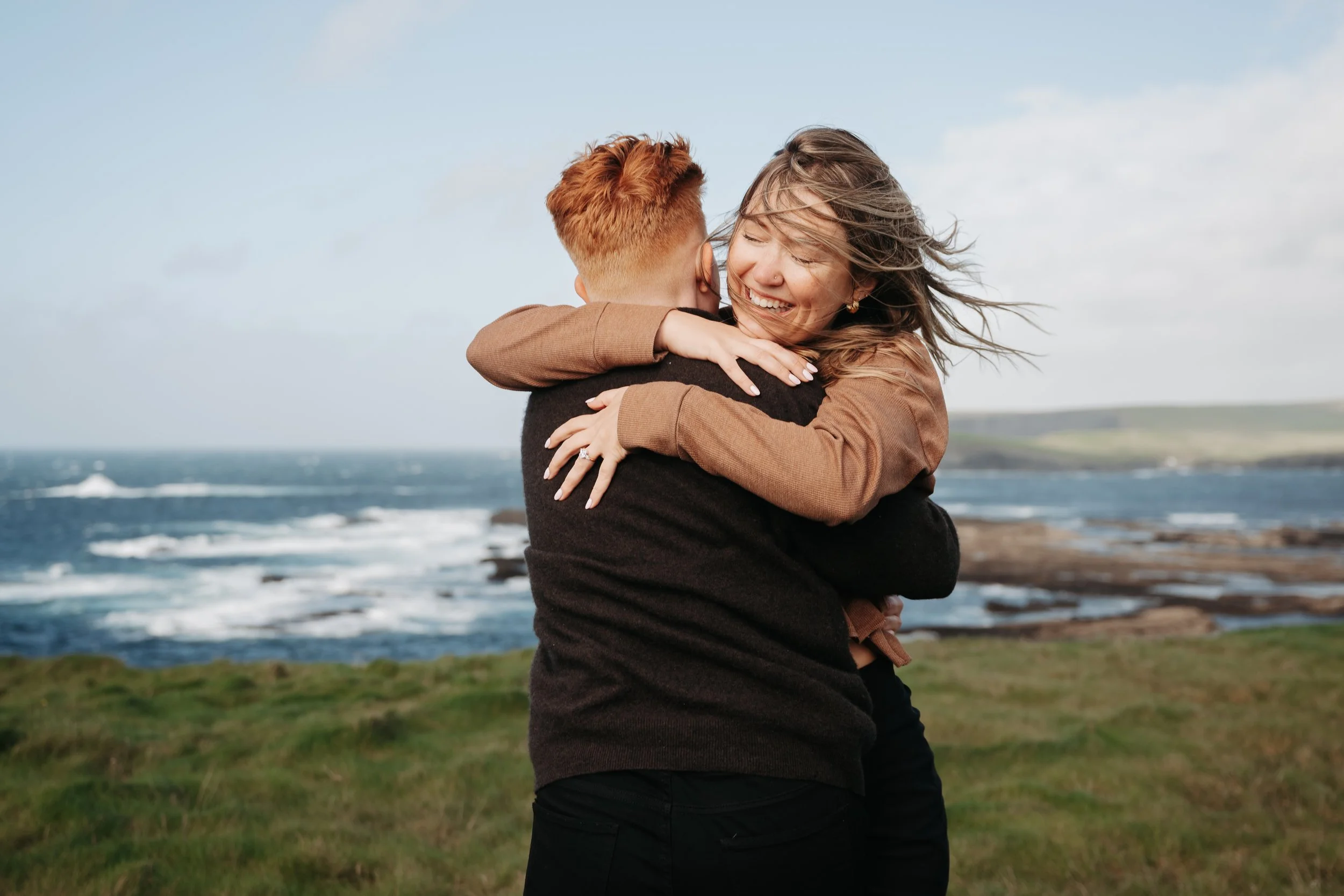 big hug of couple in kilkee getting engaged ocean and cliffs in background