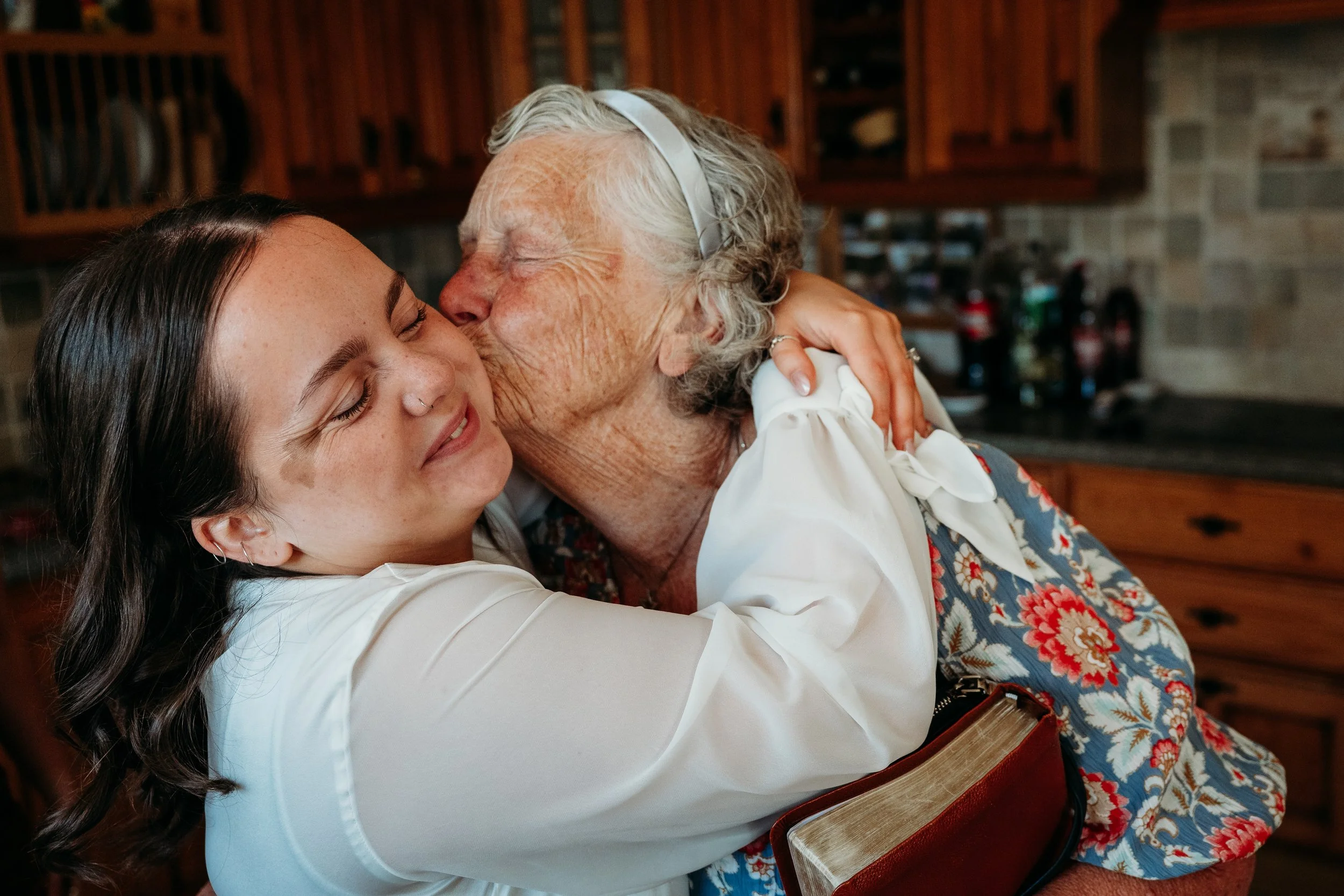 grandmother kisses bride during wedding morning getting ready photos