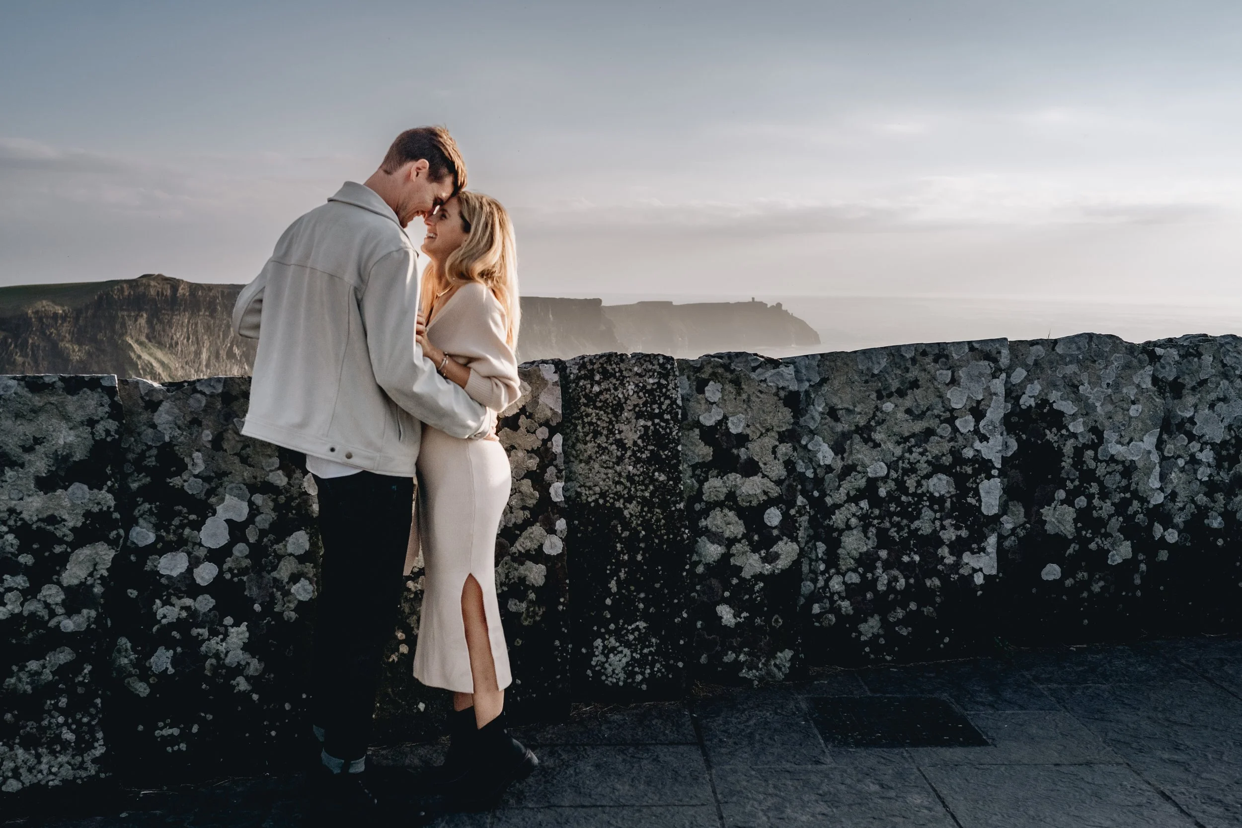 couple standing close with cliffs of moher in the background maternity photo shoot liscannor co clare